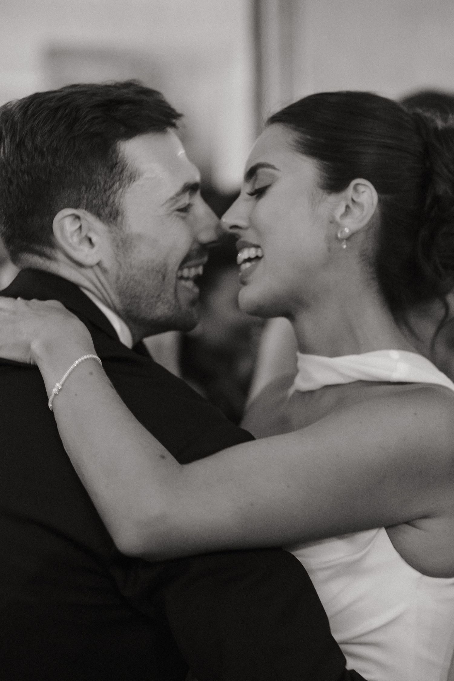 Black and white photo of a smiling bride and groom sharing an intimate first dance at their wedding reception.