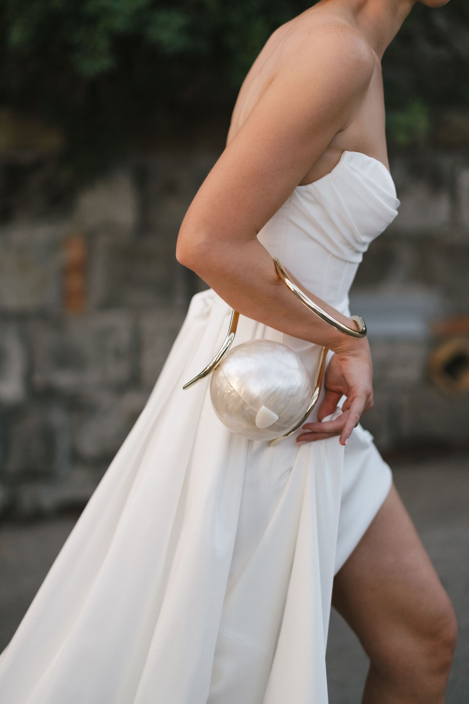 Bride in strapless white gown holding a pearl clutch bag with gold hardware.