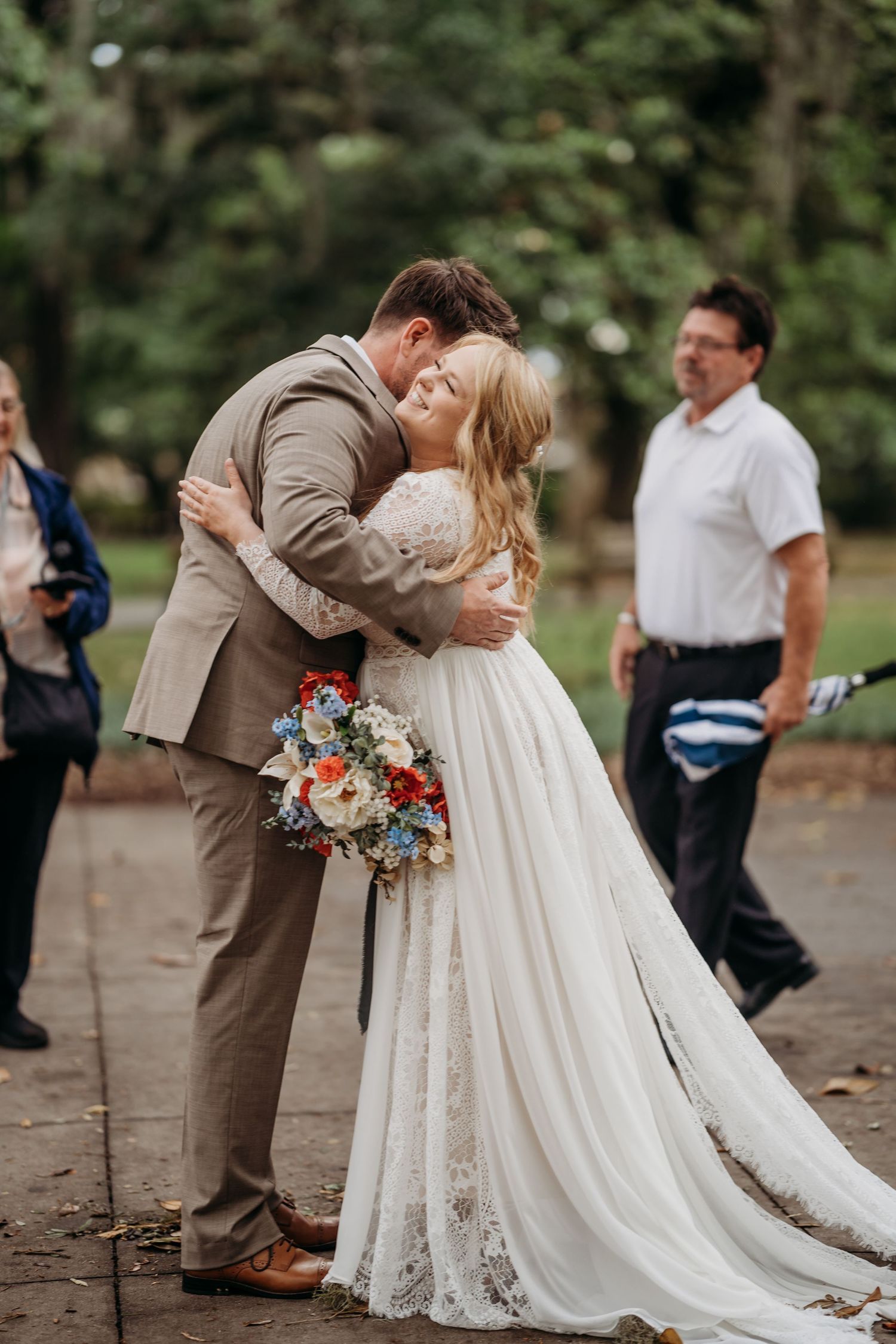 Bride and groom sharing first kiss at outdoor wedding ceremony in park.