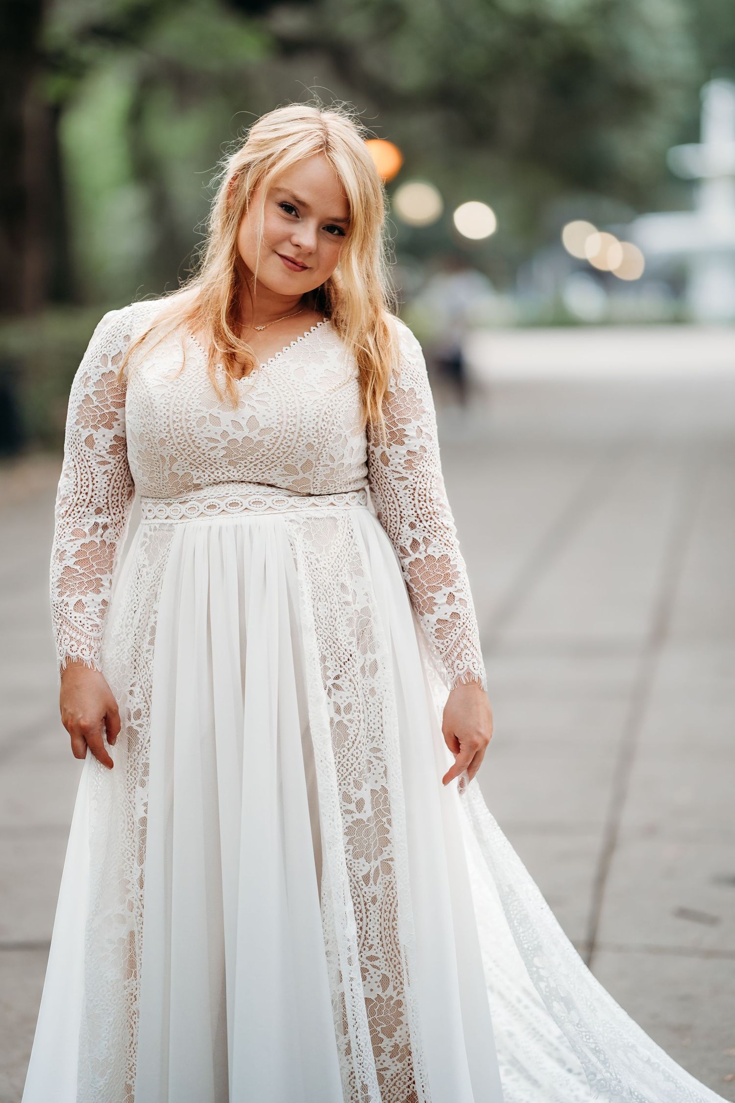 Bride in elegant long-sleeve lace wedding gown poses on outdoor pathway in Savannah, Georgia.