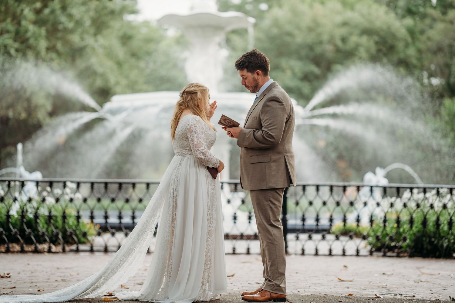 Couple reads wedding vows in front of a beautiful park fountain during their intimate elopement.