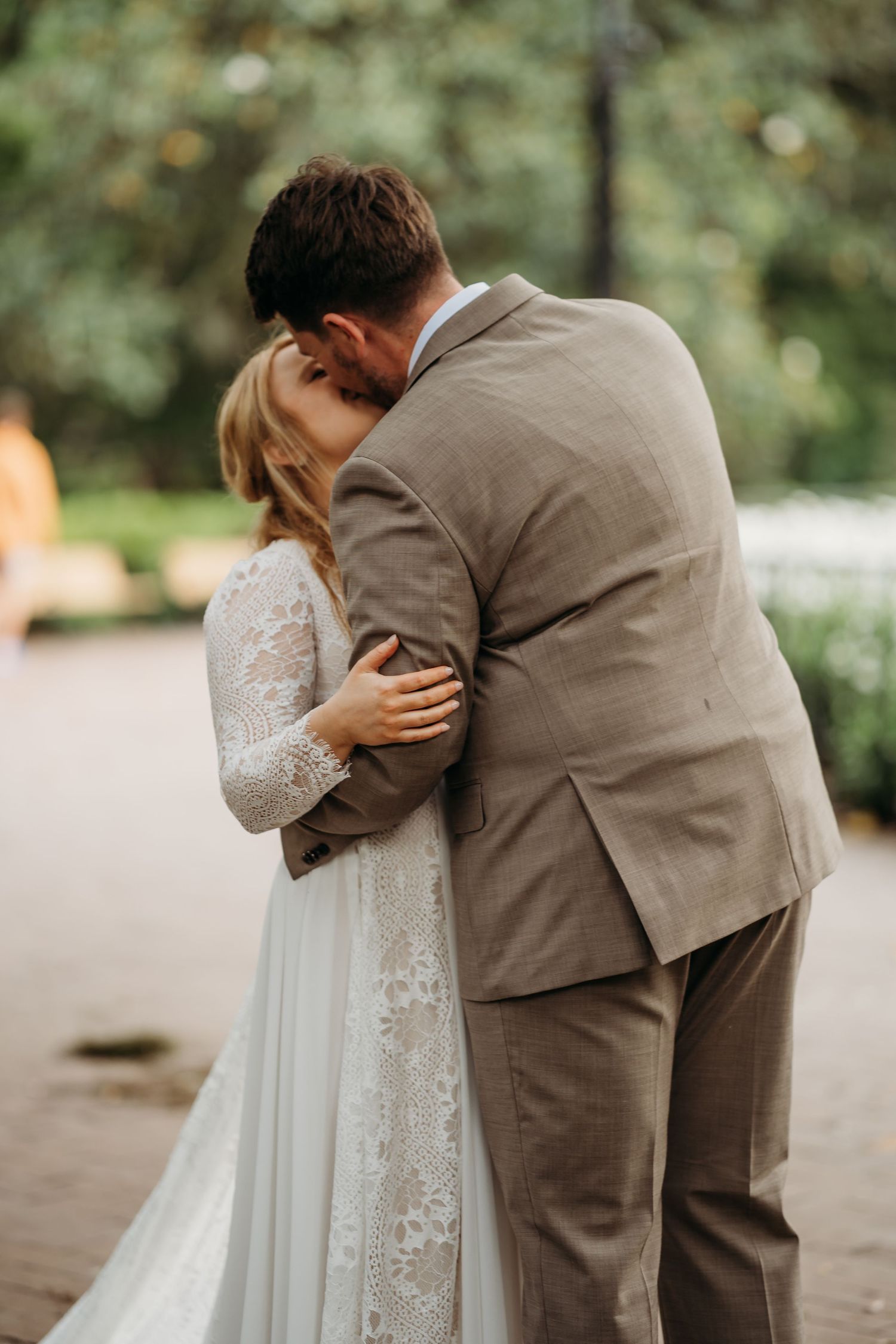 Newlyweds share their first kiss as husband and wife during an outdoor park wedding ceremony.