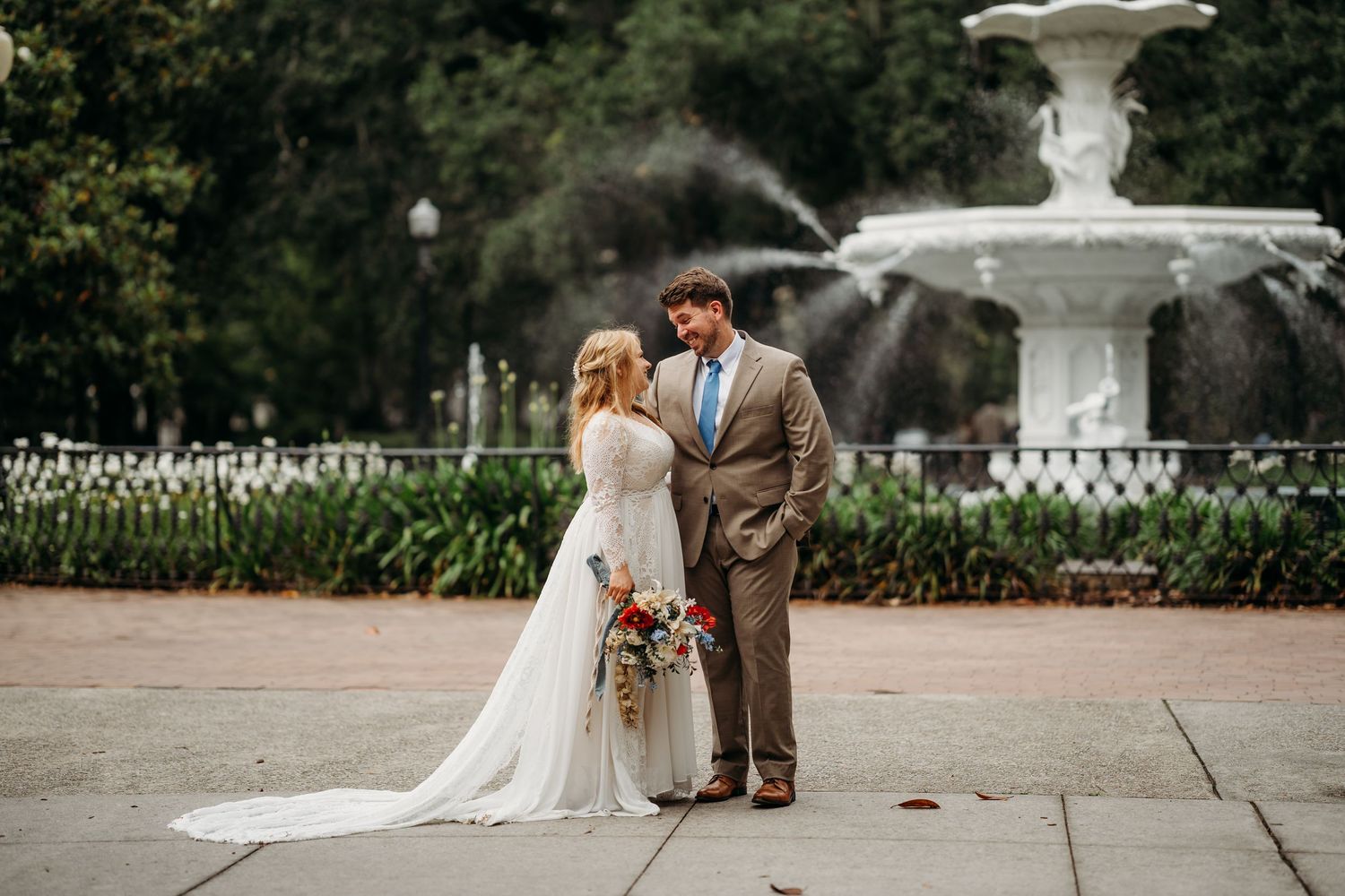 Bride and groom share an intimate moment facing each other in front of a white fountain.
