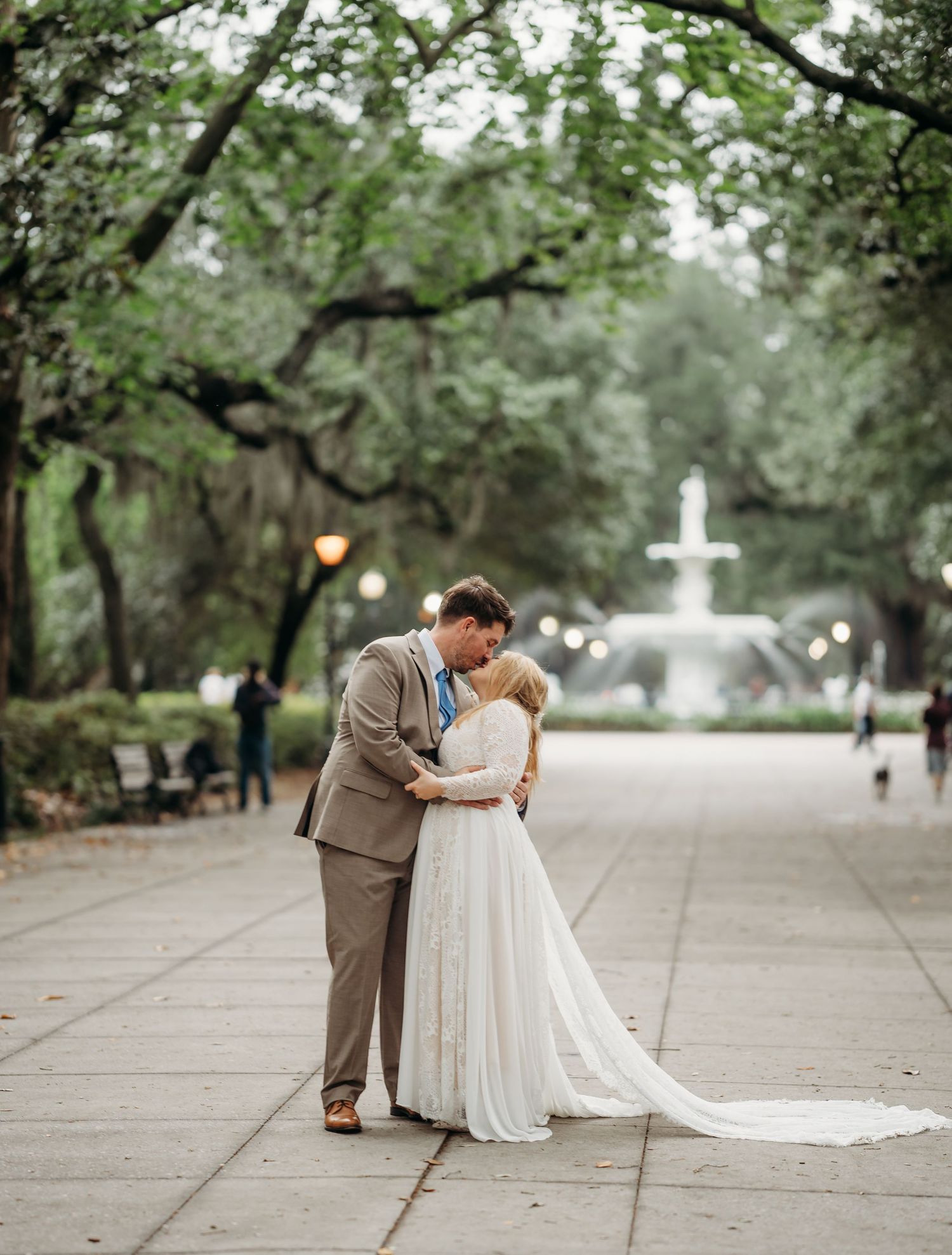 Bride and groom share romantic kiss near fountain in Forsyth Park, Savannah.