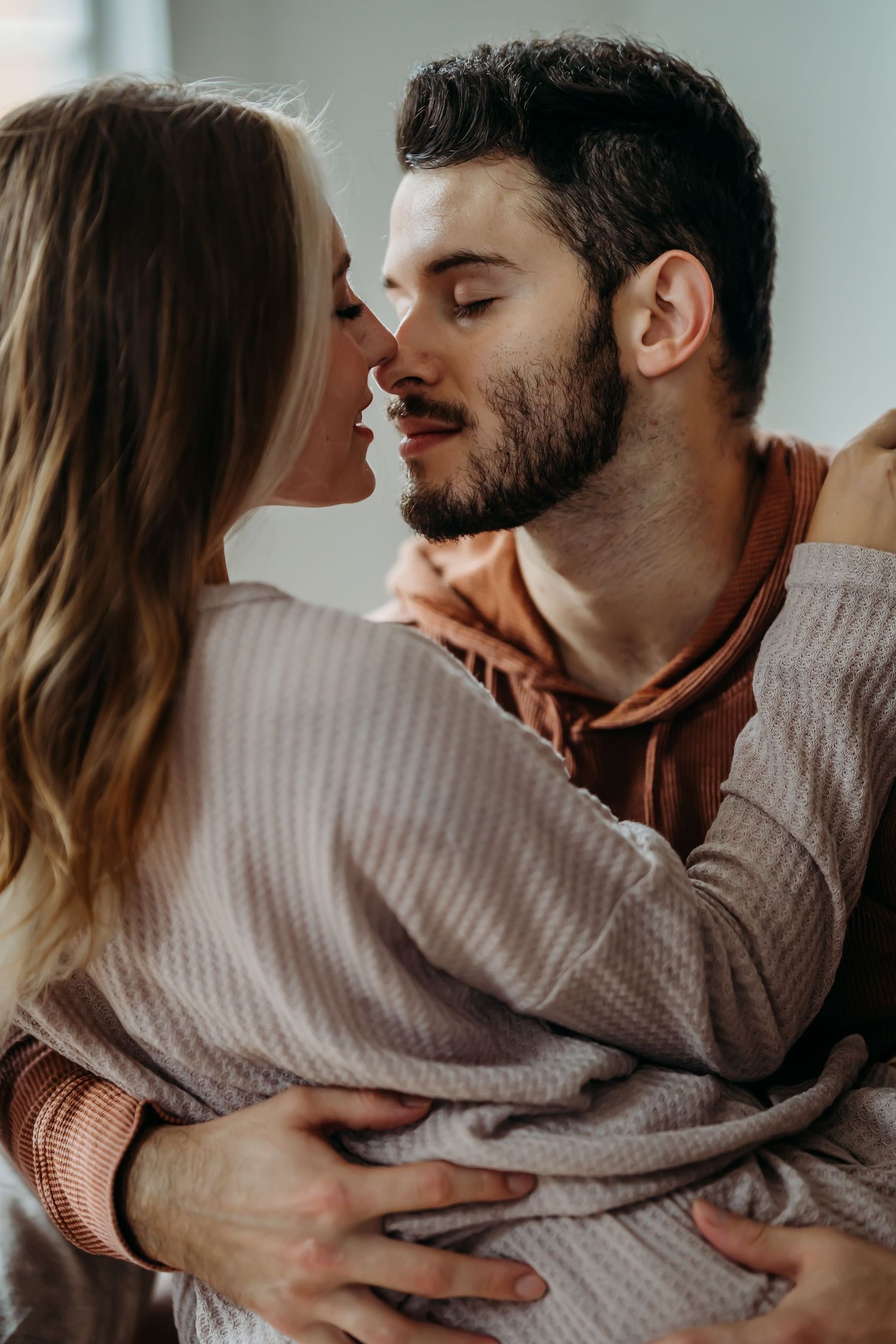 A couple shares a tender embrace, nearly kissing, with the man wrapping his arms around the woman.