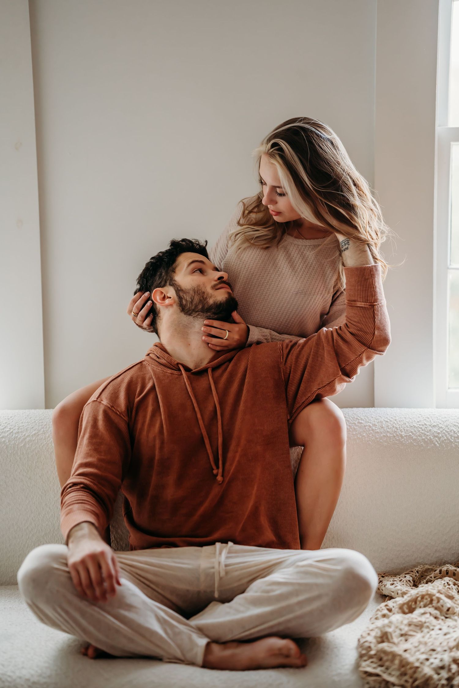 Affectionate couple sitting together on couch, woman gently holding mans face.