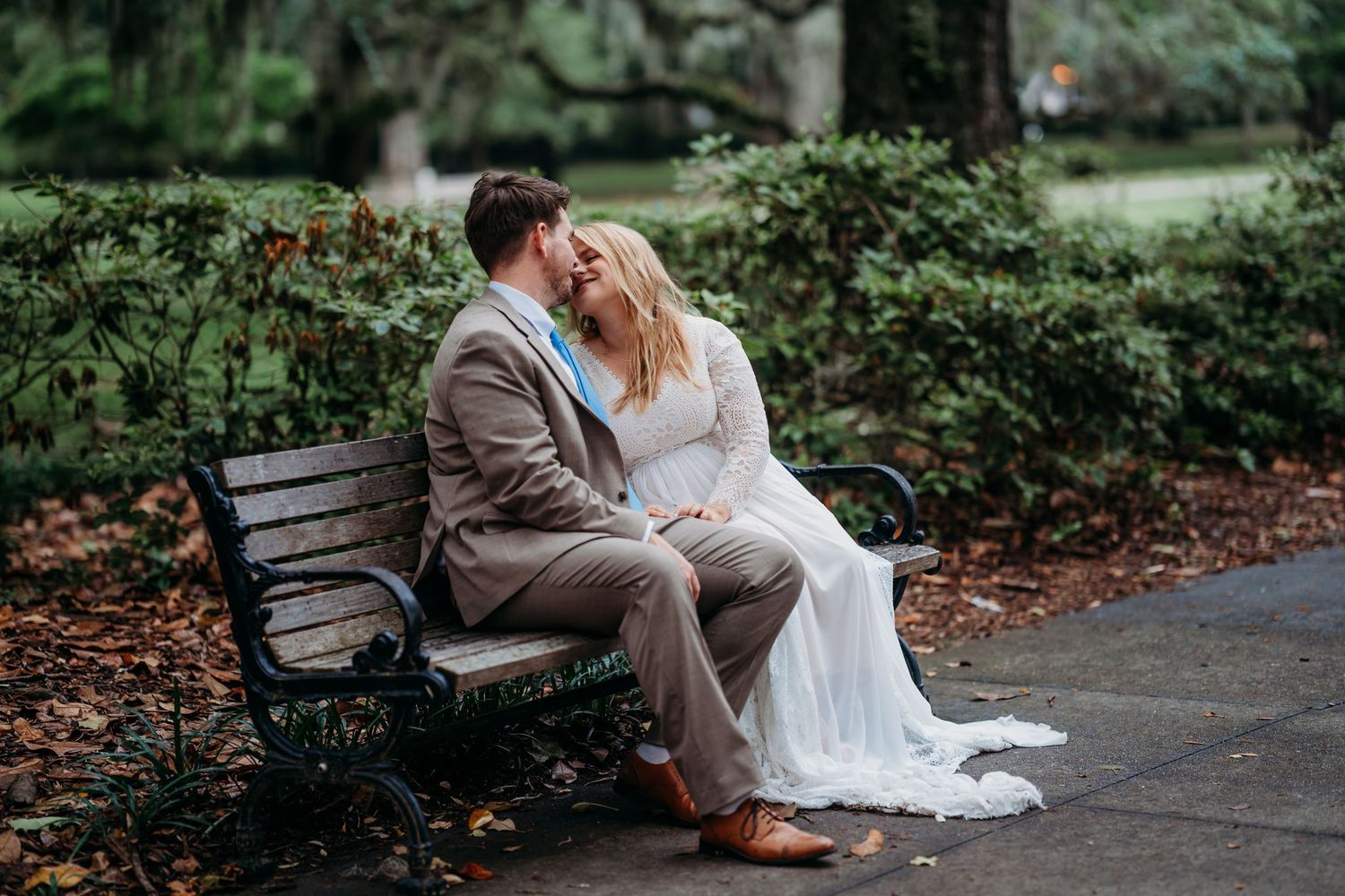 Newlyweds sitting close together on a park bench, sharing a loving moment in autumn surroundings.