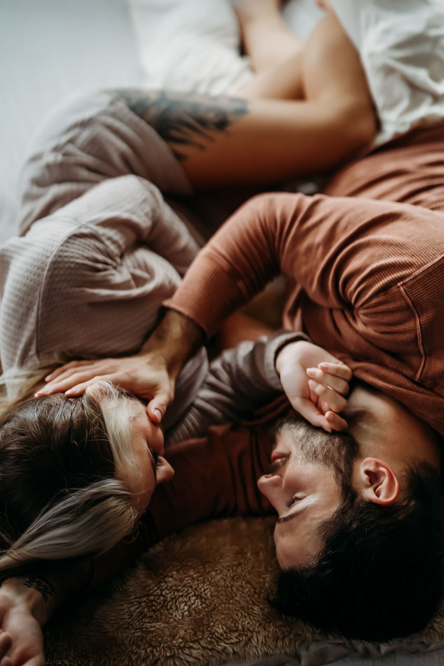 Couple lying on floor together holding a baby, captured from above in warm tones.