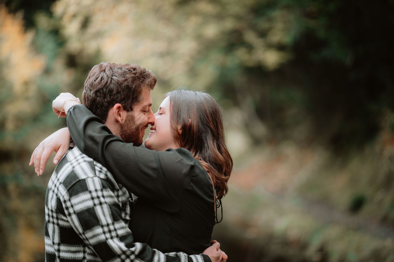 Happy couple embracing and smiling at each other in a romantic outdoor nature setting.