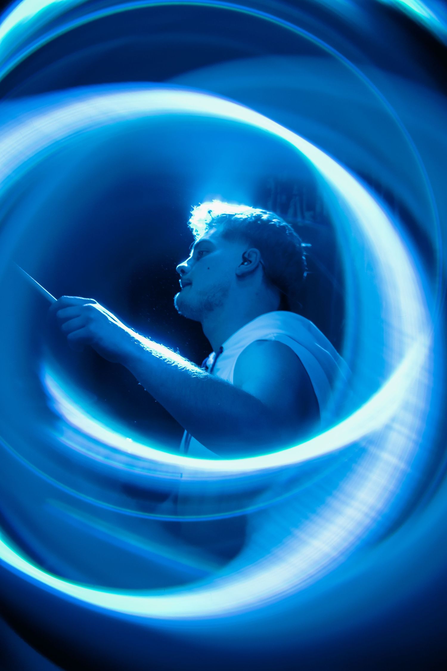 Drummer captured with swirling blue light trails during an energetic live performance.