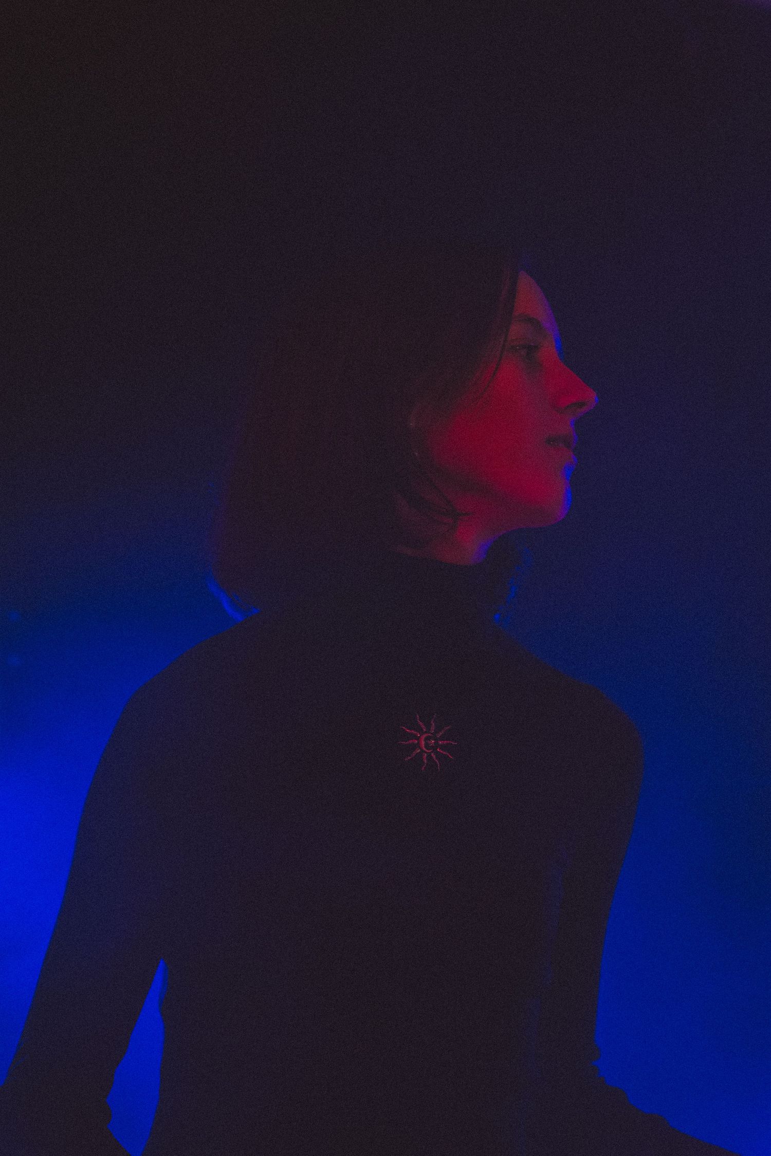 Artistic silhouette of woman with short hair against blue and red dramatic lighting background.