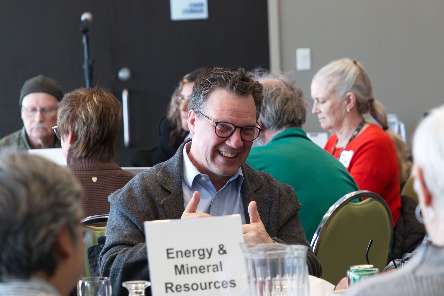 A photo at a corporate event with someone giving a thumbs-up to the camera