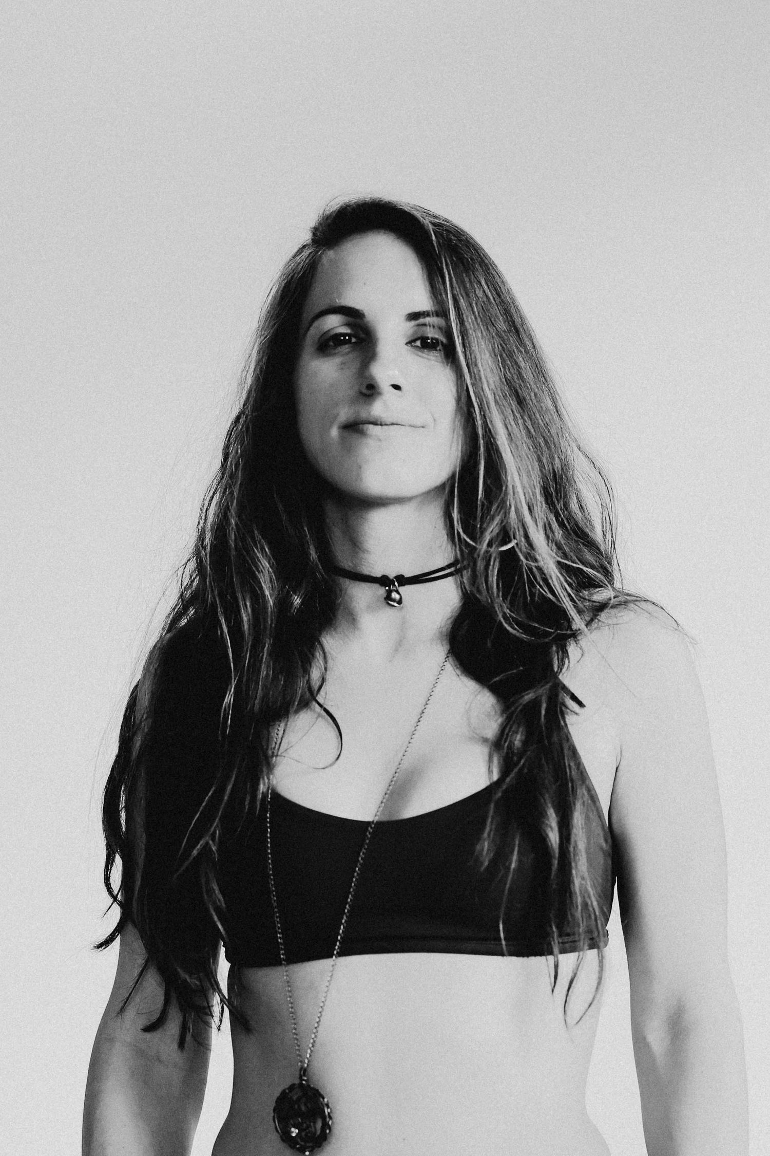 Black and white portrait of woman with long hair wearing a black crop top and choker necklace.