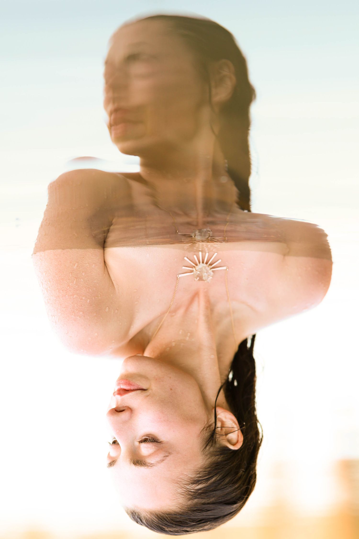 Artistic double exposure portrait of a woman with sun flare creating dreamy surreal photography effect.