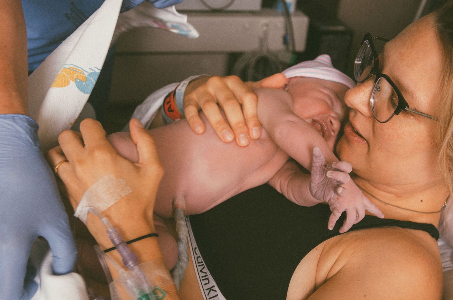 Mother kissing her newborn baby immediately after birth in a hospital delivery room.
