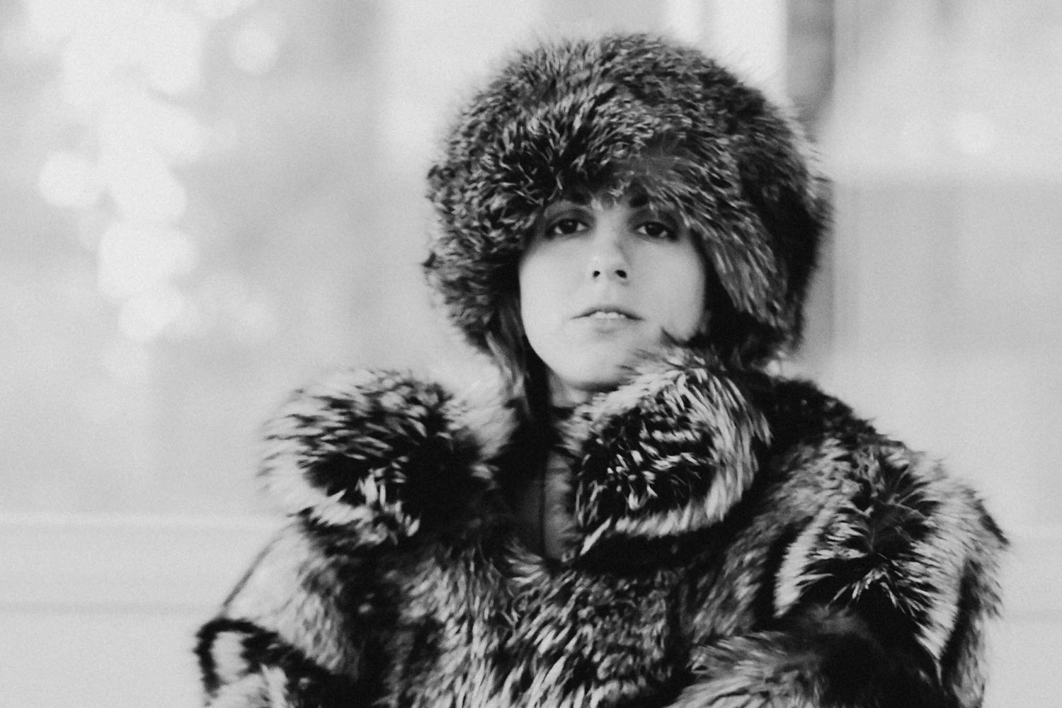 Black and white portrait of a woman wearing a luxurious fur hat and coat in winter.