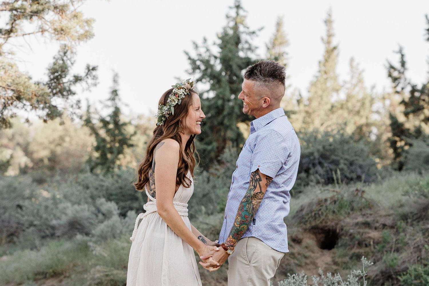 Couple holding hands and gazing at each other in a natural outdoor setting.