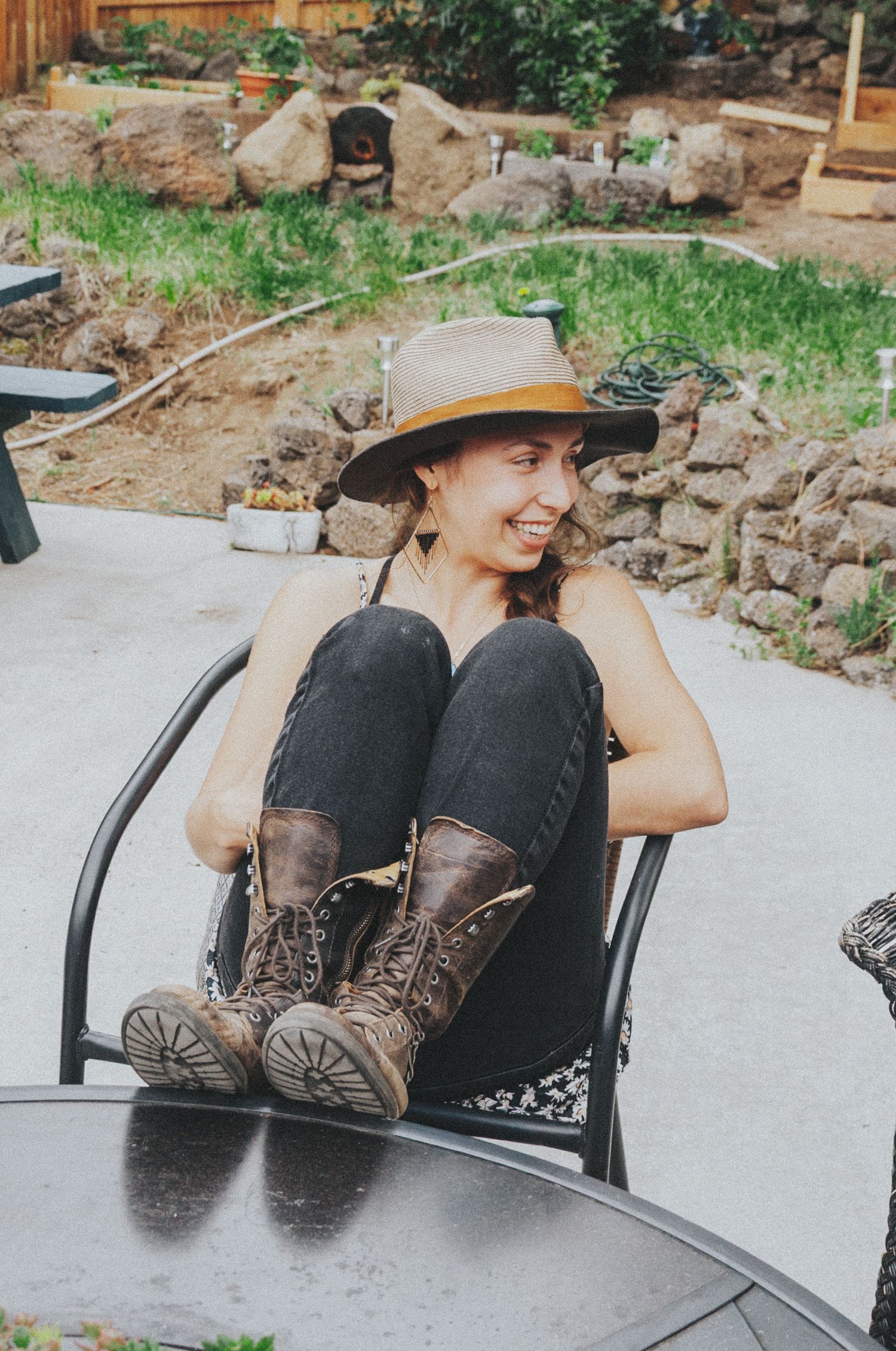 Smiling woman in brown hat relaxing in chair with boots up.