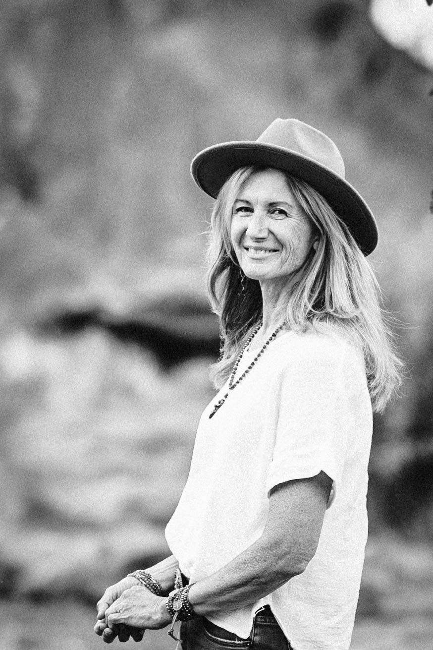 Black and white portrait of smiling woman in hat outdoors.