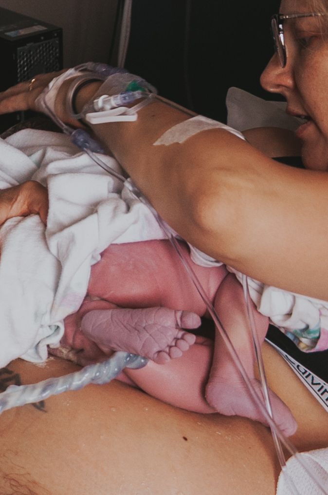 Mother gazing at newborn baby's tiny feet in hospital after birth.