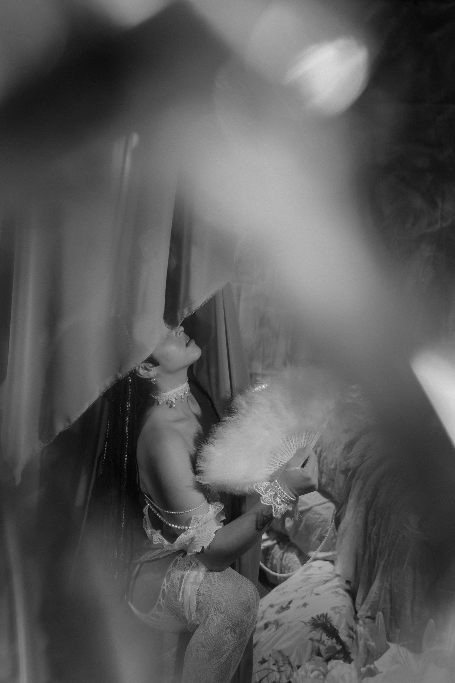 Black and white vintage photo of a woman in 1920s costume with feather fan, looking upward dramatically.