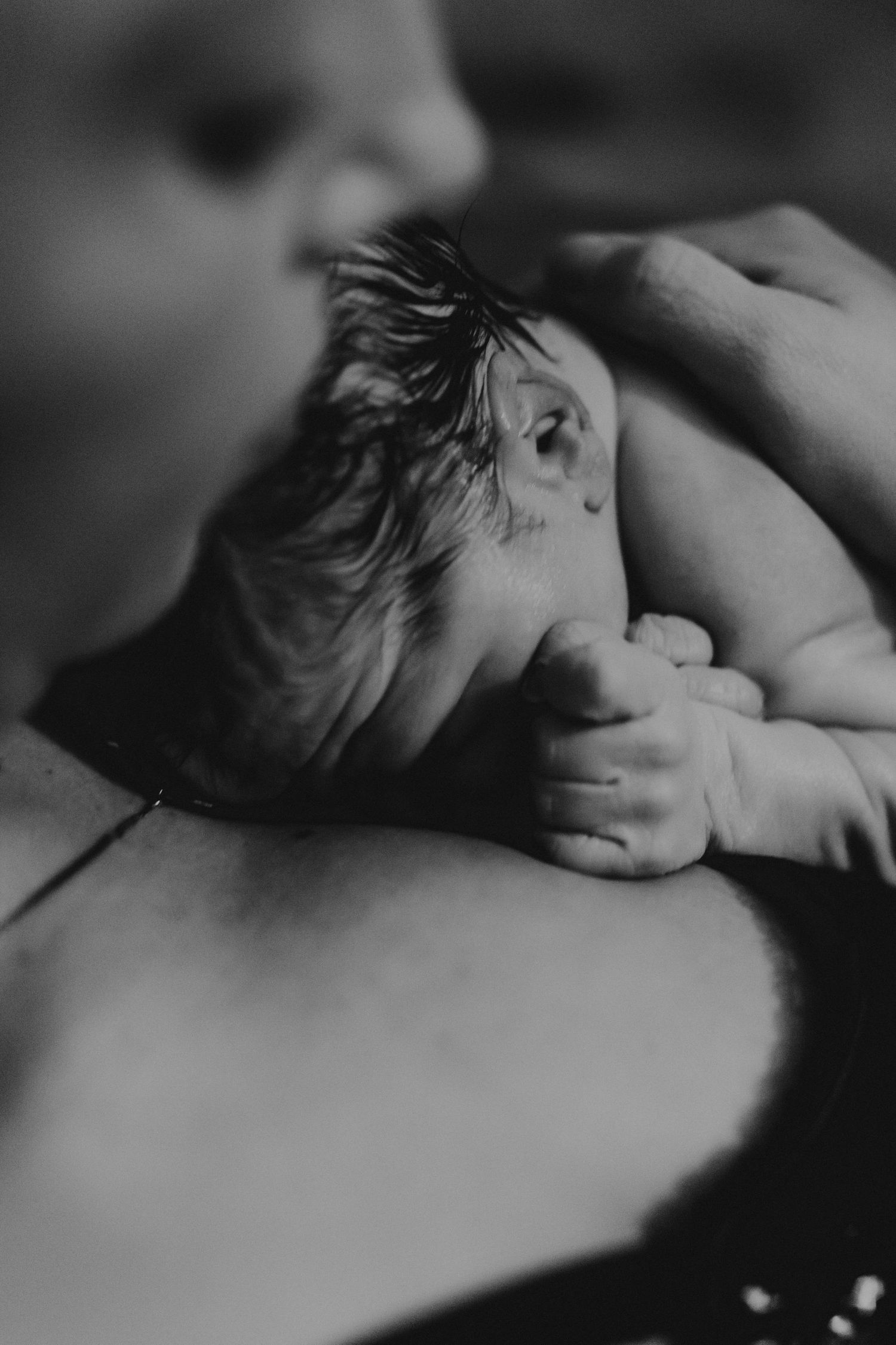 Black and white newborn baby resting on mother's chest moments after birth. top rated RI birth photographer