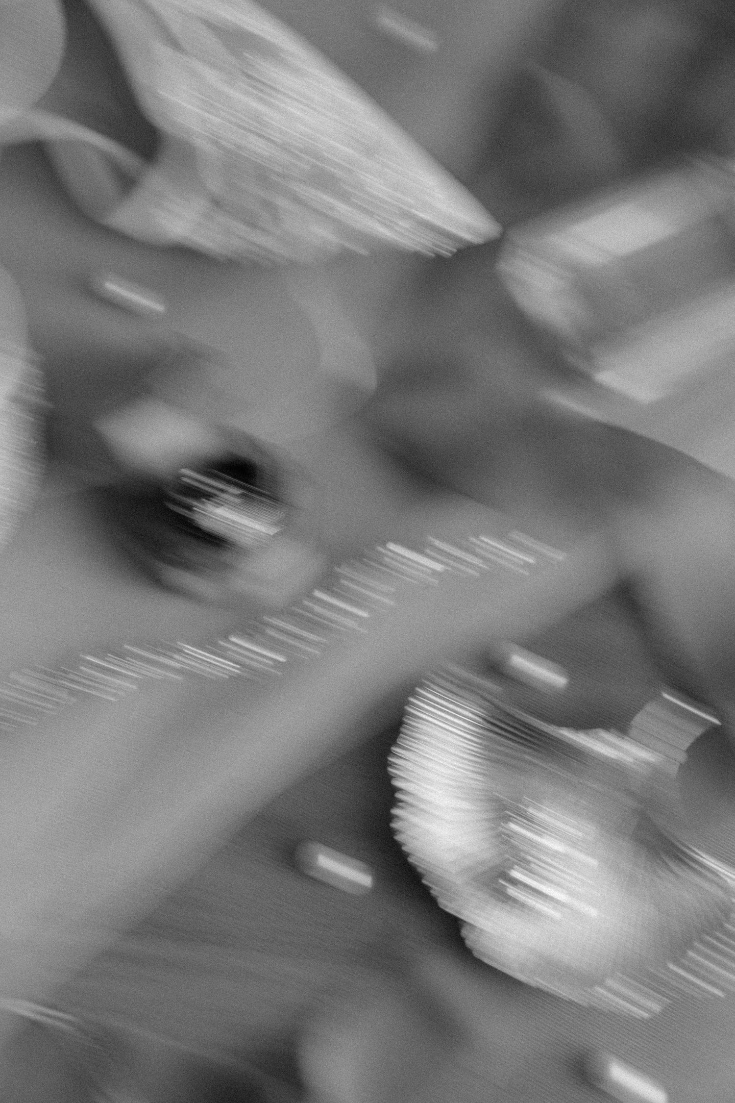 Abstract black and white motion blur photograph of seashells and wedding details on a textured surface.