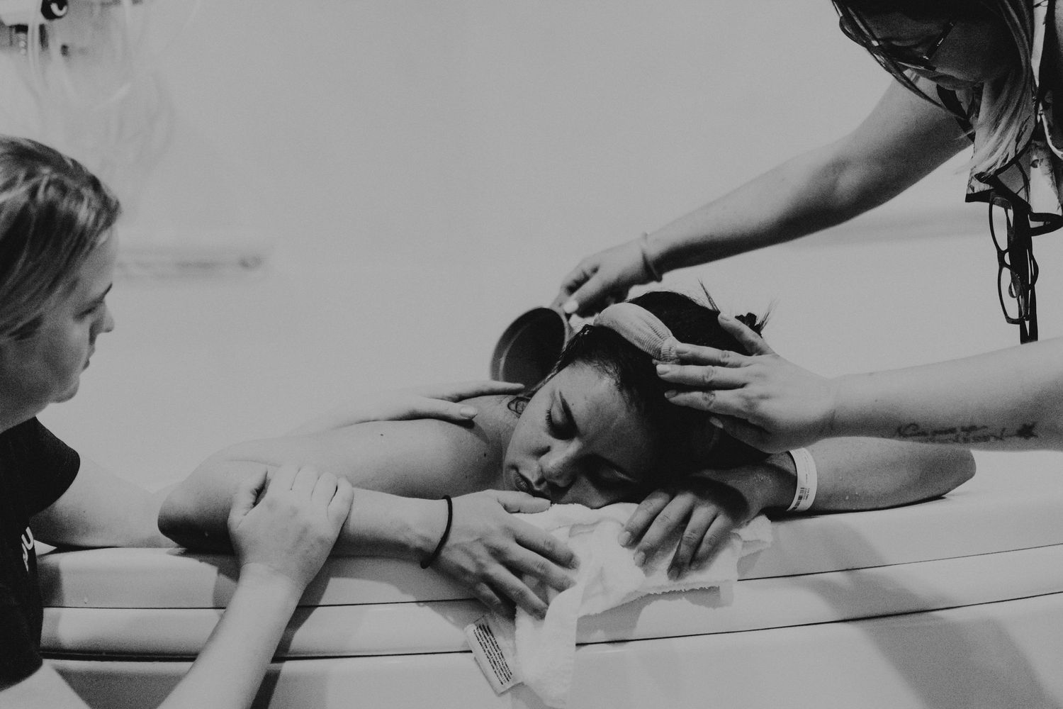 Black and white image of woman during labor receiving support from birth attendants. top rated RI birth photographer