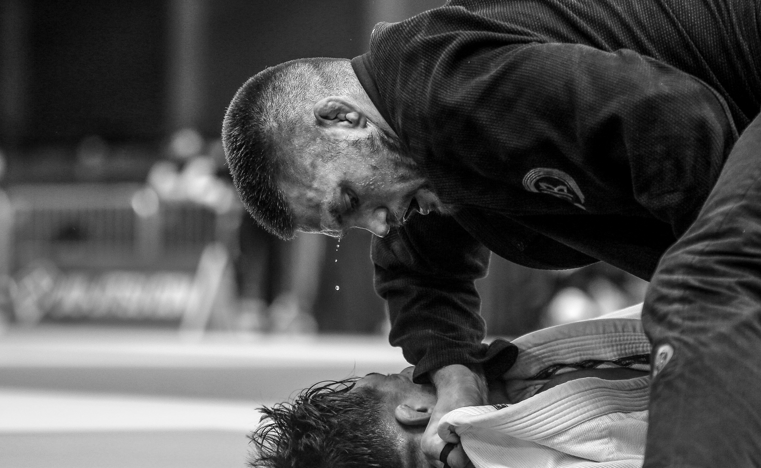 Two athletes competing in a Brazilian jiu-jitsu match, captured in dramatic black and white photography.