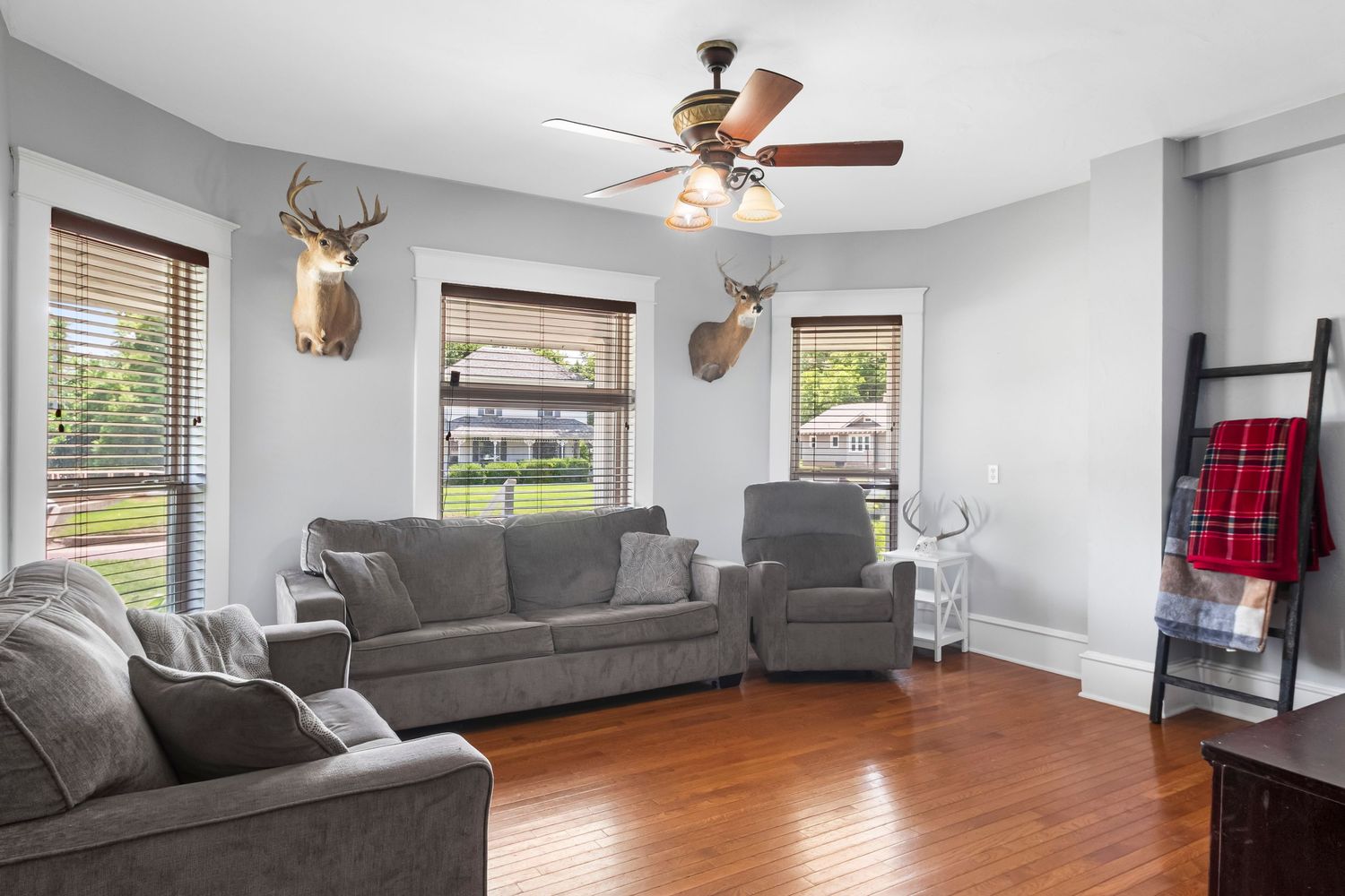 Spacious living area with gray sofas, hardwood floors, and deer head wall decor.