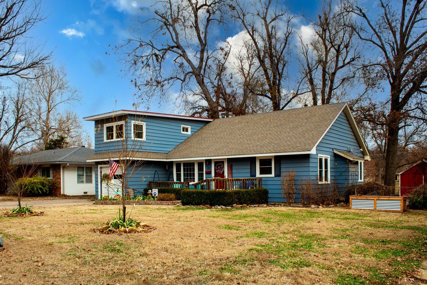 Winter landscape view of residential homes with bare trees against blue sky.