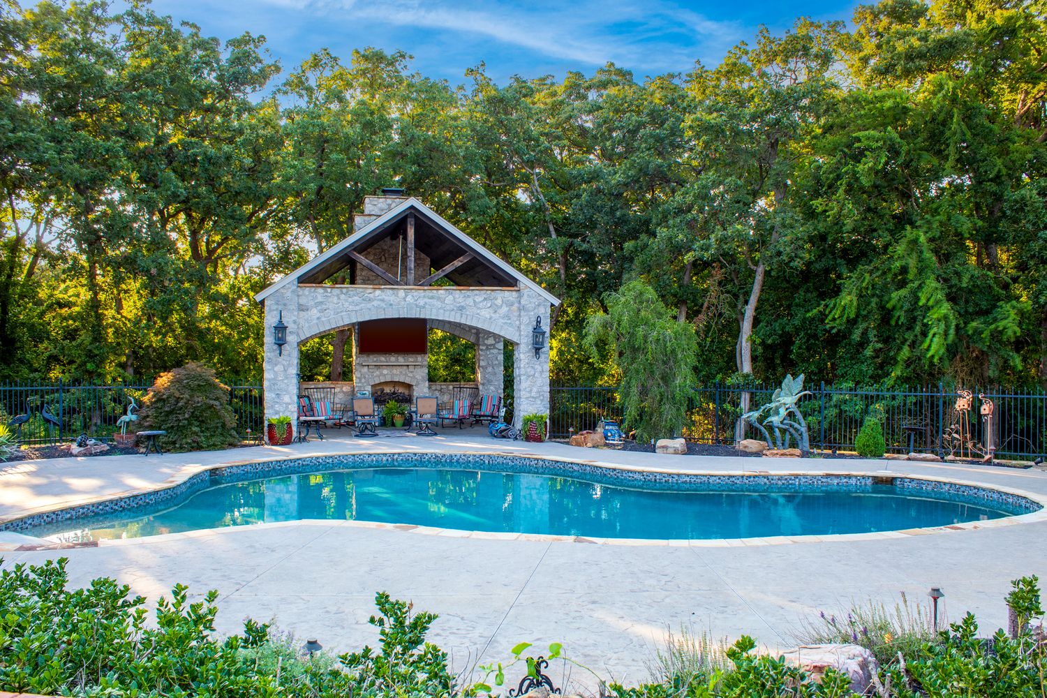 Expansive outdoor pool area surrounded by lush greenery and landscaping features.