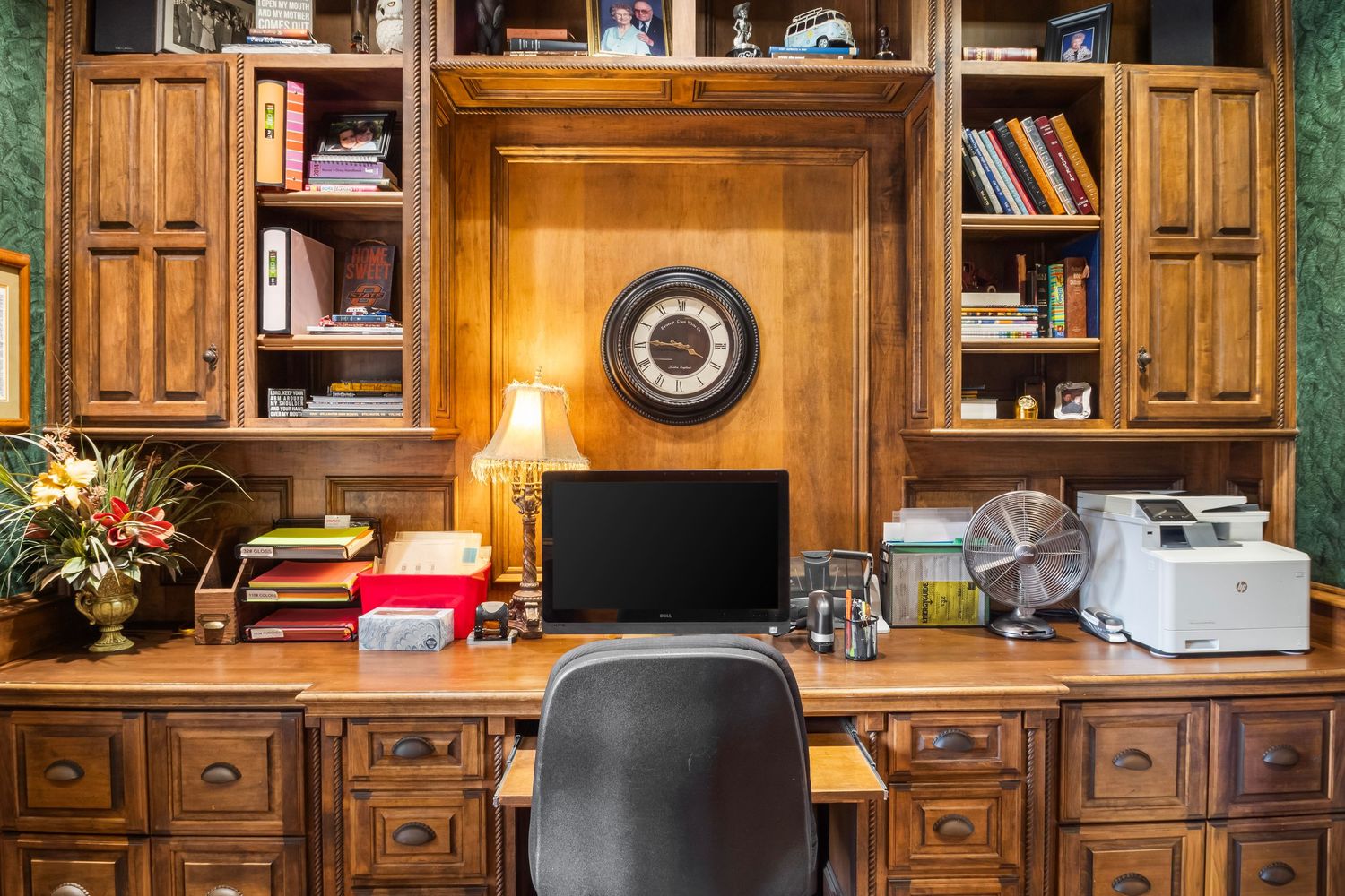 Custom built-in wood office shelving and cabinetry with desk space and traditional decor.