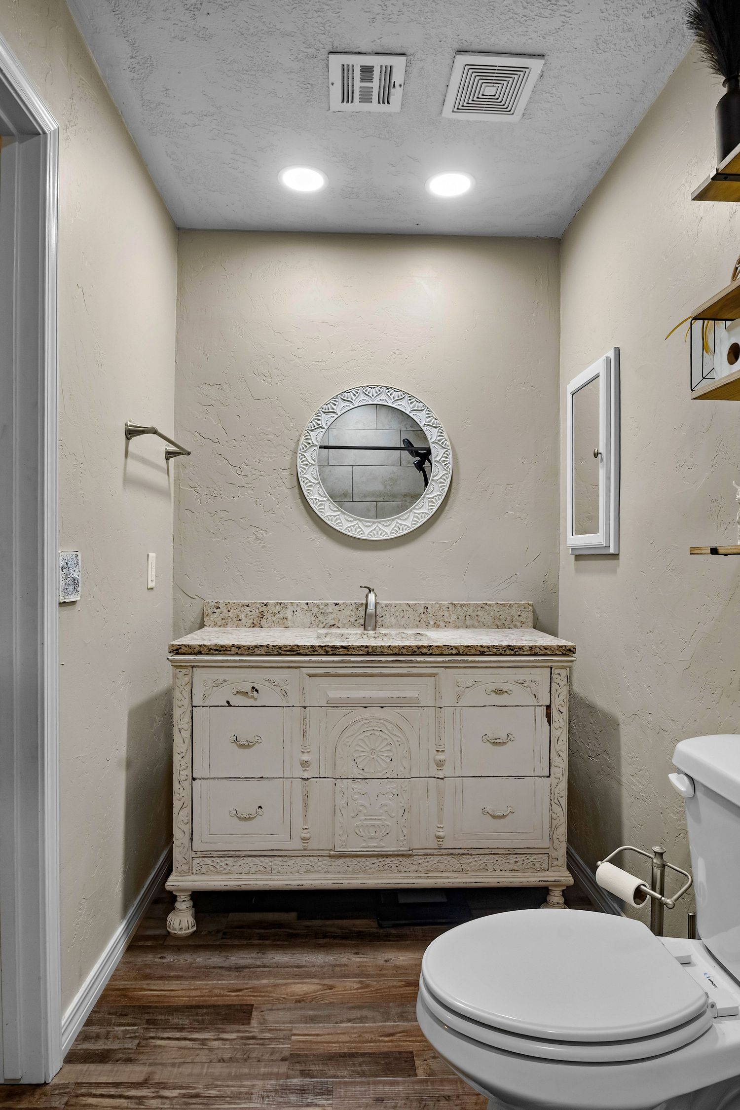 Elegant bathroom with vintage-style vanity, granite countertop, and wood flooring.