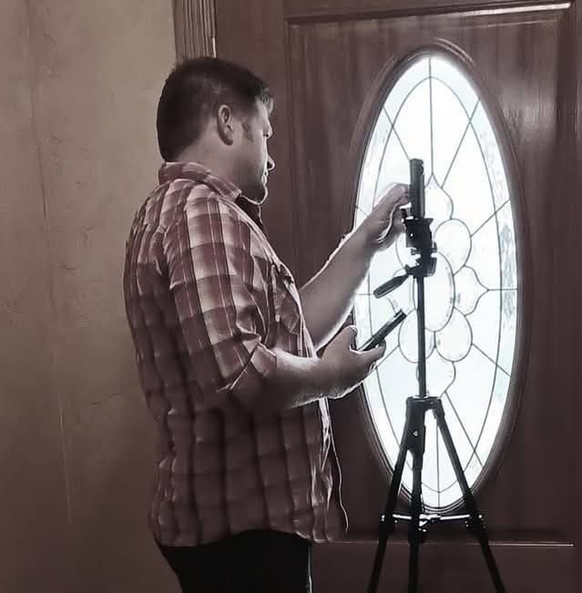 Person inspecting a large circular window in a dark wood-paneled room.