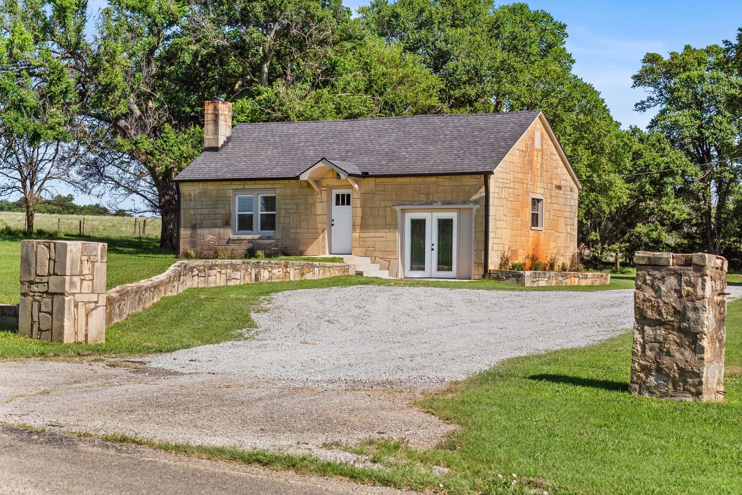 Charming stone and wood cottage with gravel driveway and walkout basement entrance.