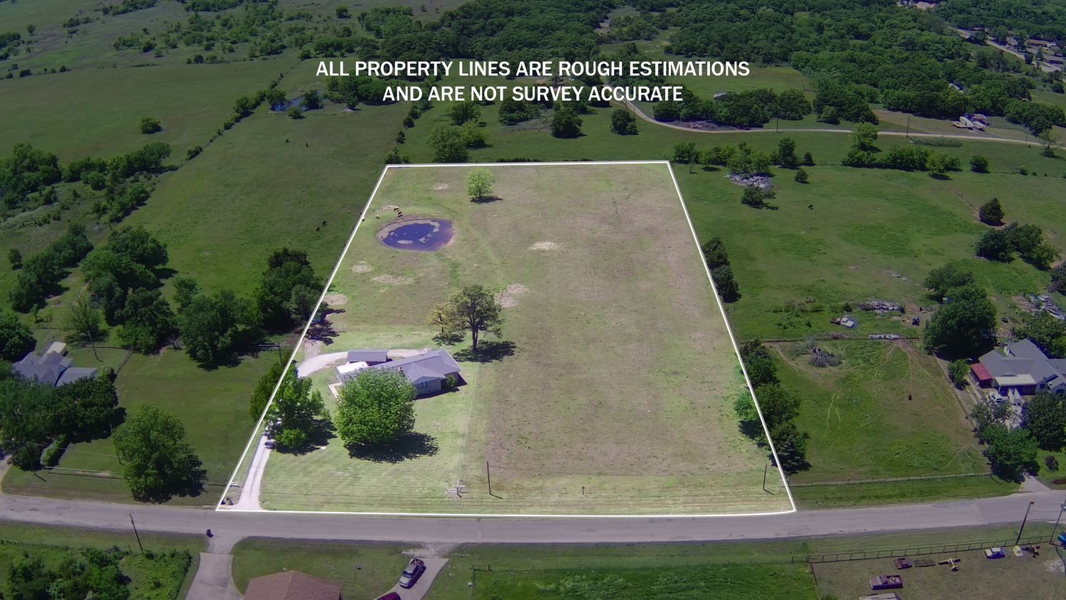 Aerial view of a large rural property lot with scattered trees and a road frontage.