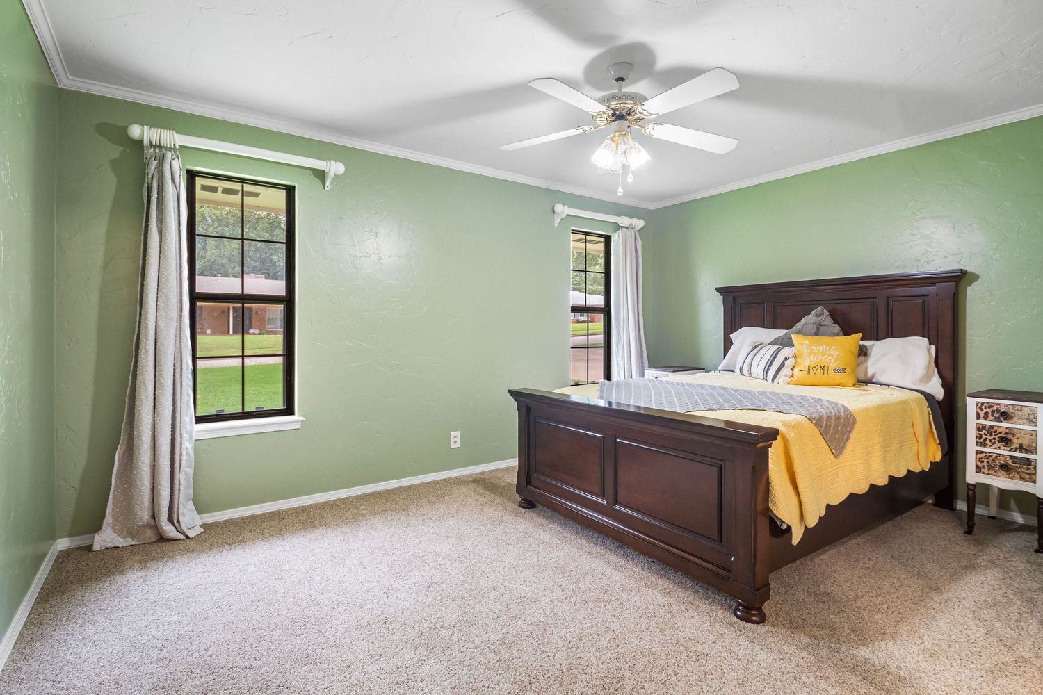 Bedroom with mint green walls, ceiling fan, and large windows providing natural light.