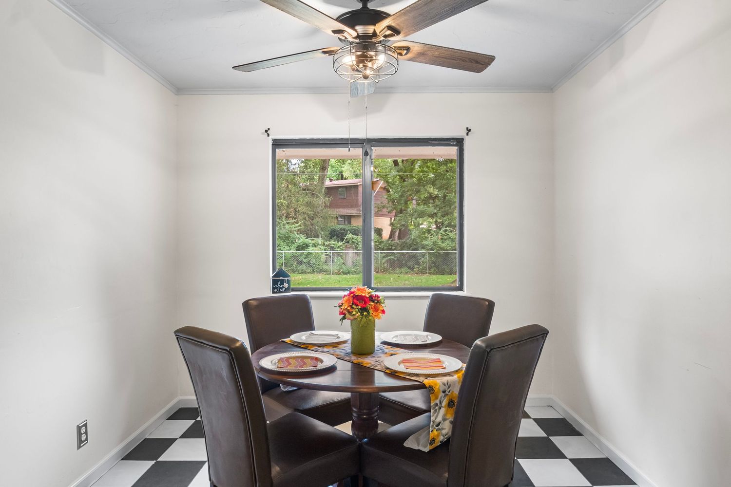 Dining area with ceiling fan featuring a round table and chairs near window with outdoor view.