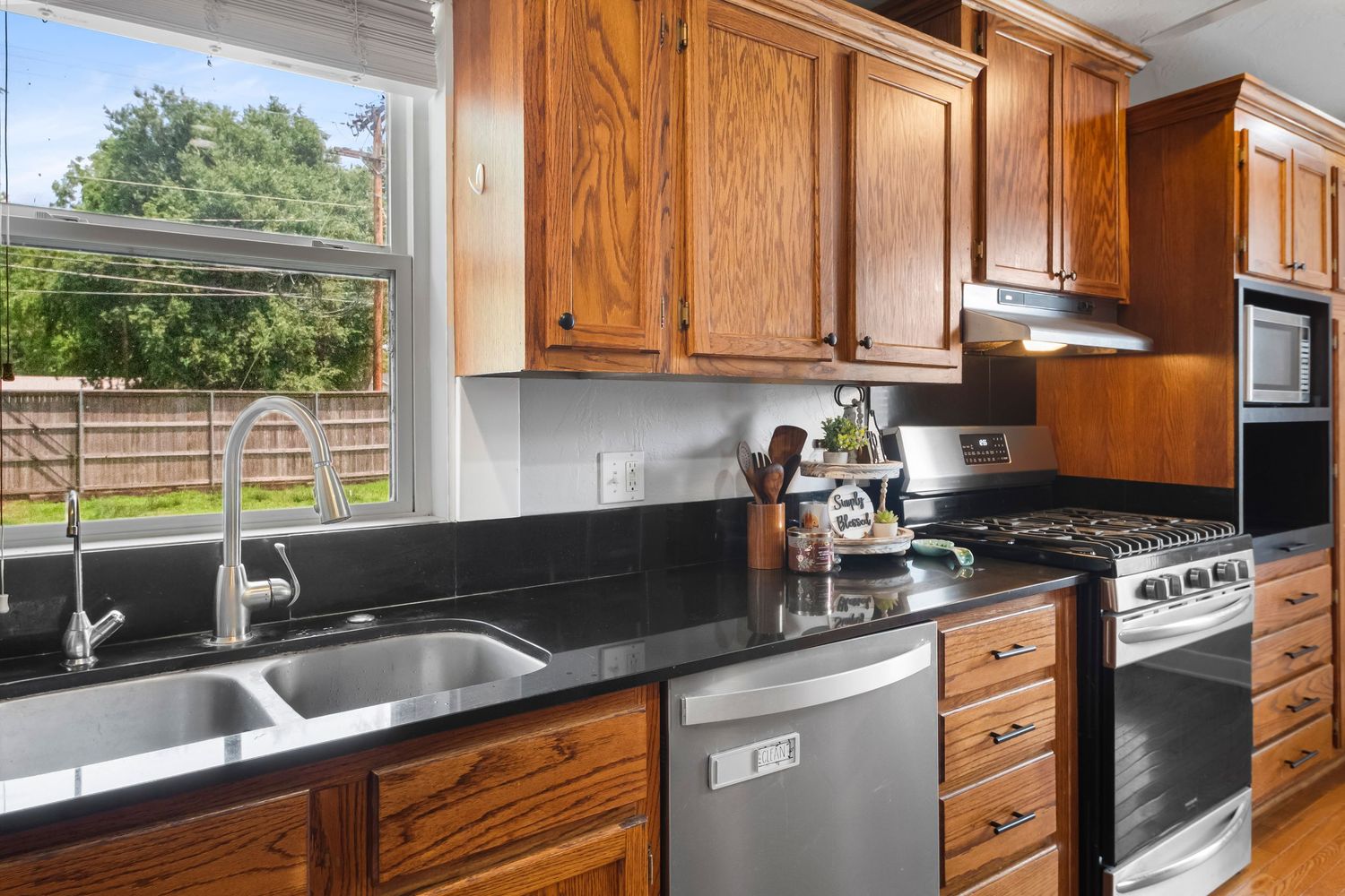 Modern kitchen with dark granite countertops and wooden cabinets.