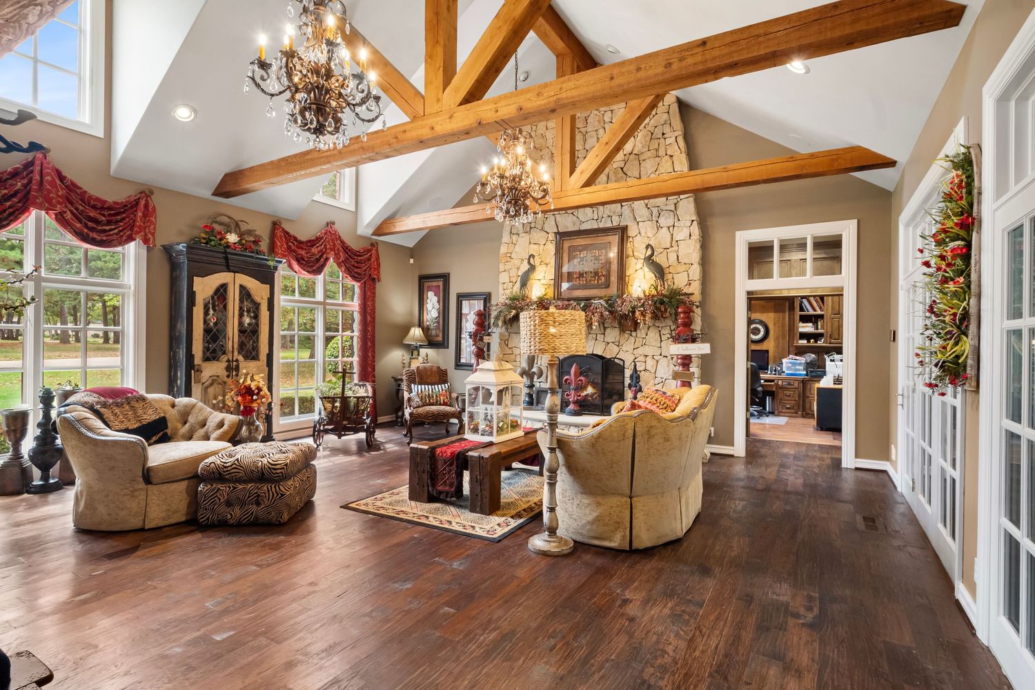 Spacious great room with exposed wooden beams, elegant furnishings, and large windows.