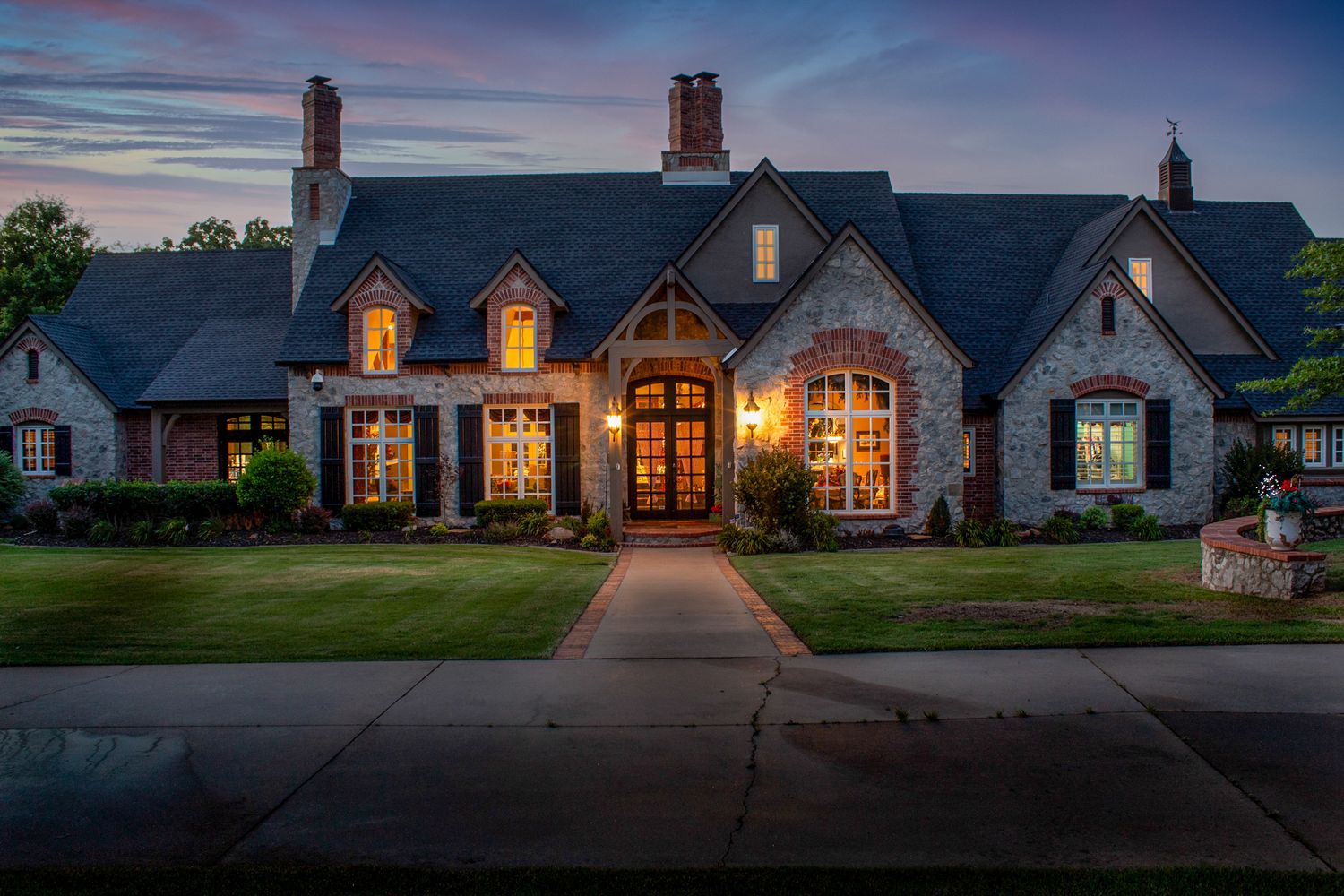 Panoramic twilight view of a grand country estate with warm exterior lighting.