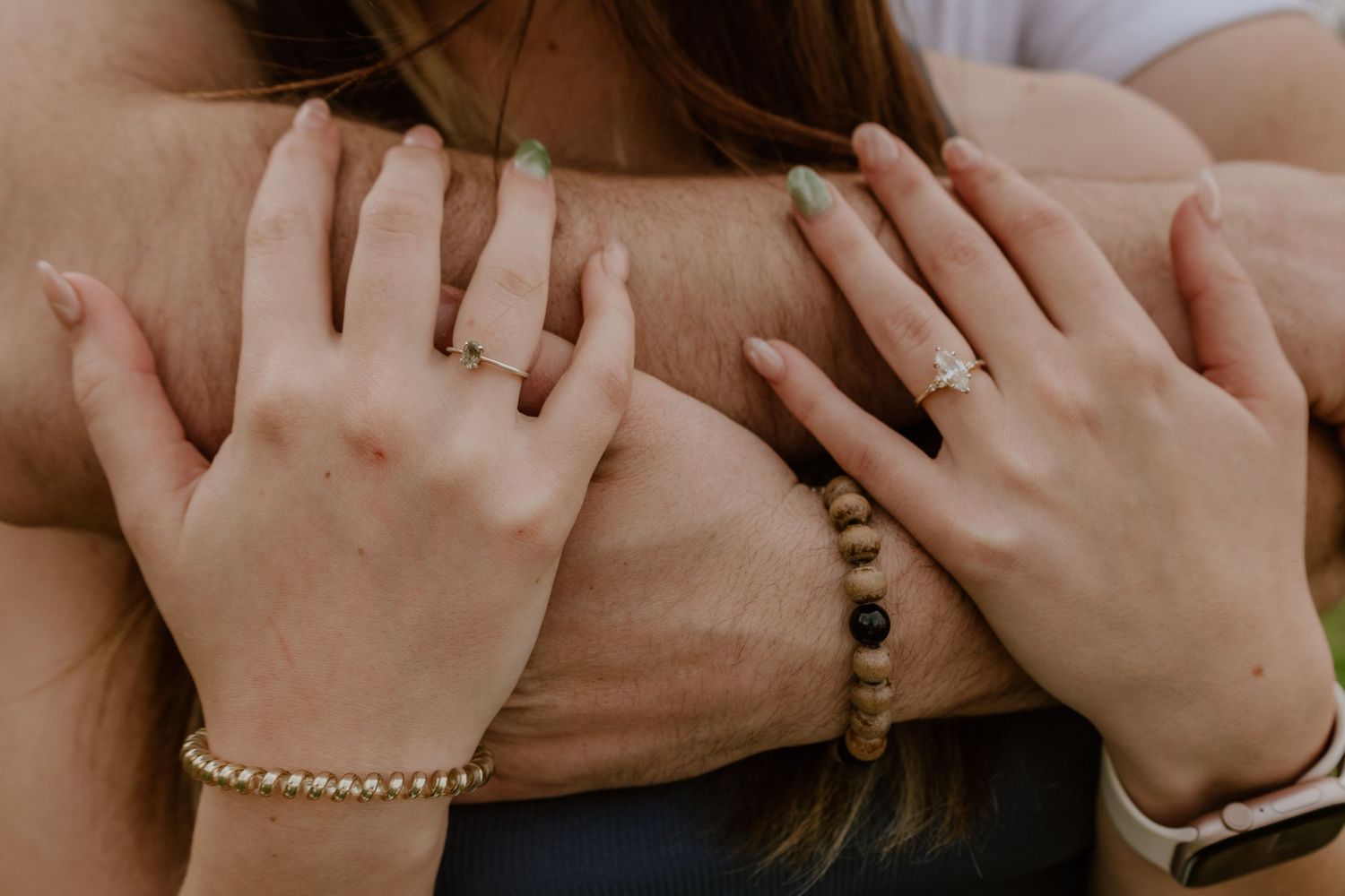 A row of hands holding onto a wooden railing, showing unity and connection in a group setting.