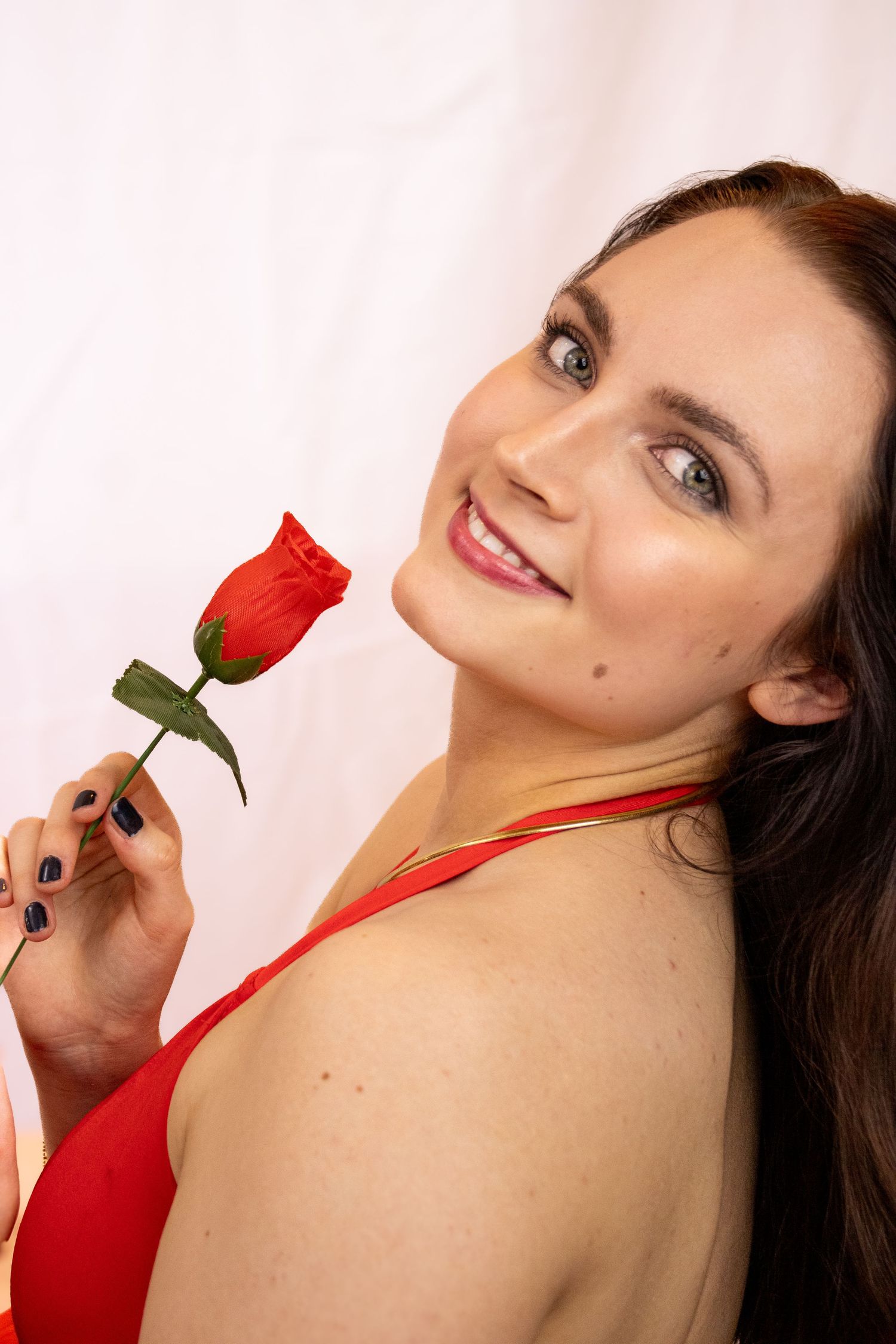 A person in a red top poses with a red rose in a series of artistic portrait shots against a light background.