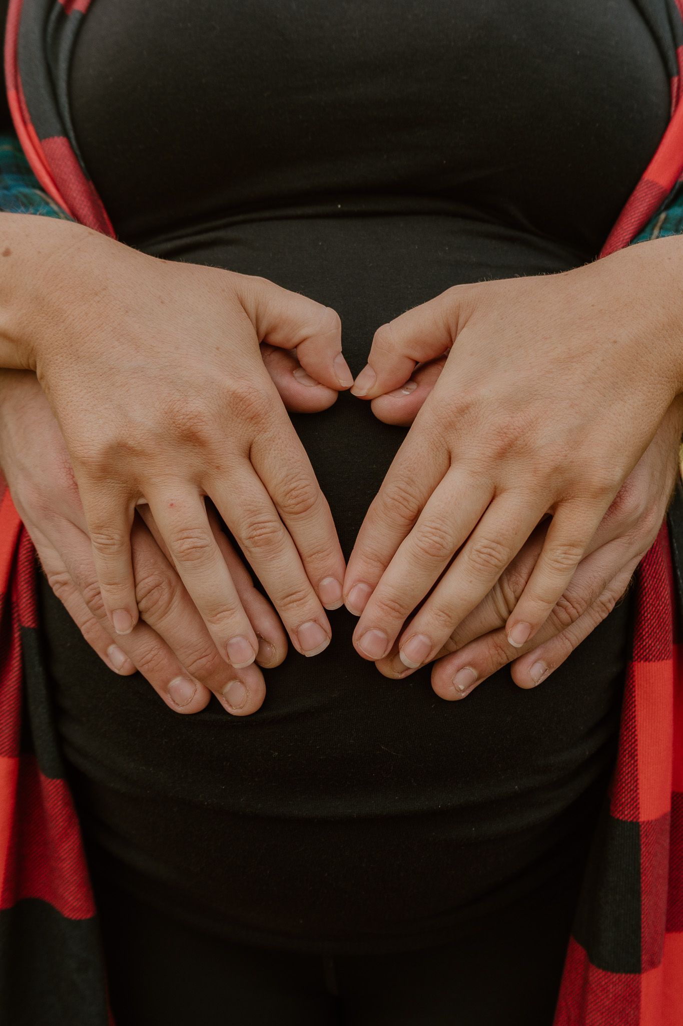 Close-up of hands resting on a black dress with red stripes in a delicate, feminine pose.