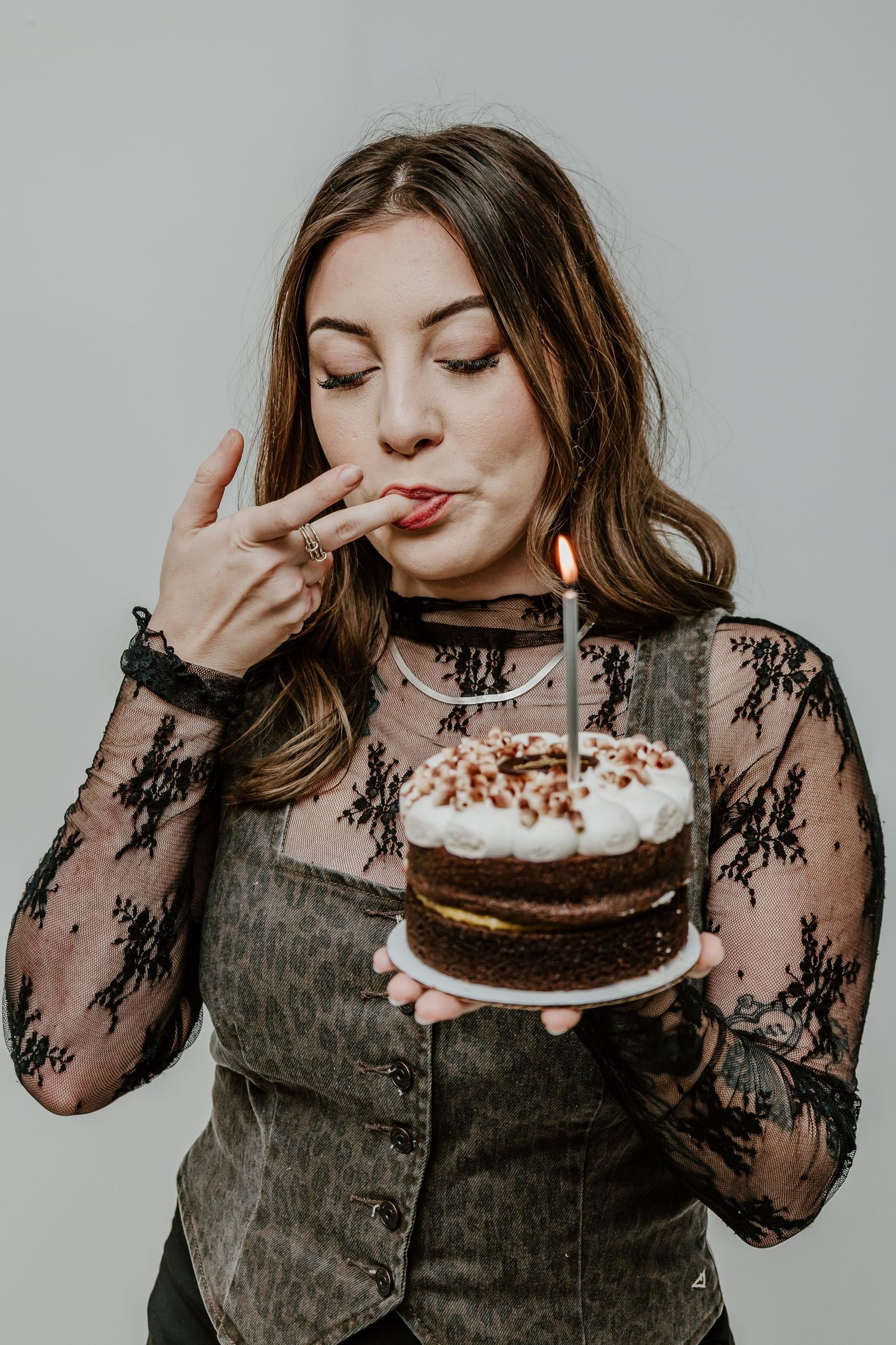 A sequence of photos showing someone in black lace holding and playfully eating a chocolate birthday cake.