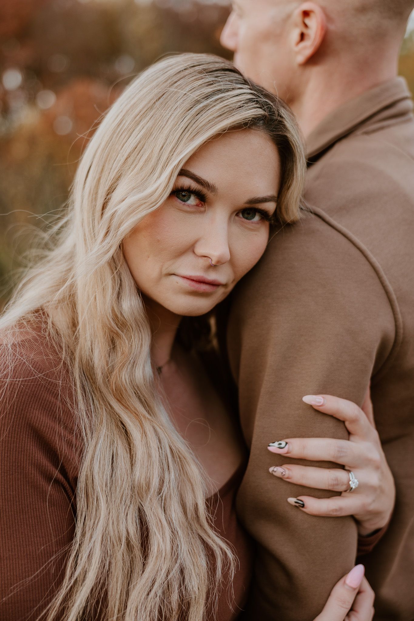 A romantic autumn engagement photoshoot showing close-up details of a couple in brown sweaters and a diamond ring.
