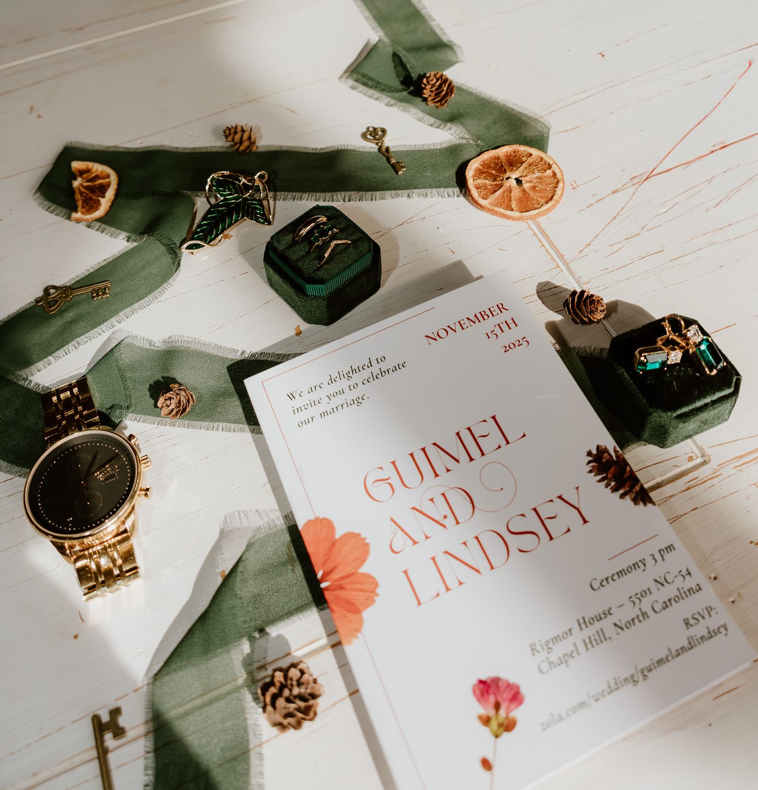 Wedding invitation suite with dried orange slices, delicate ribbons, and floral details arranged on white surface.