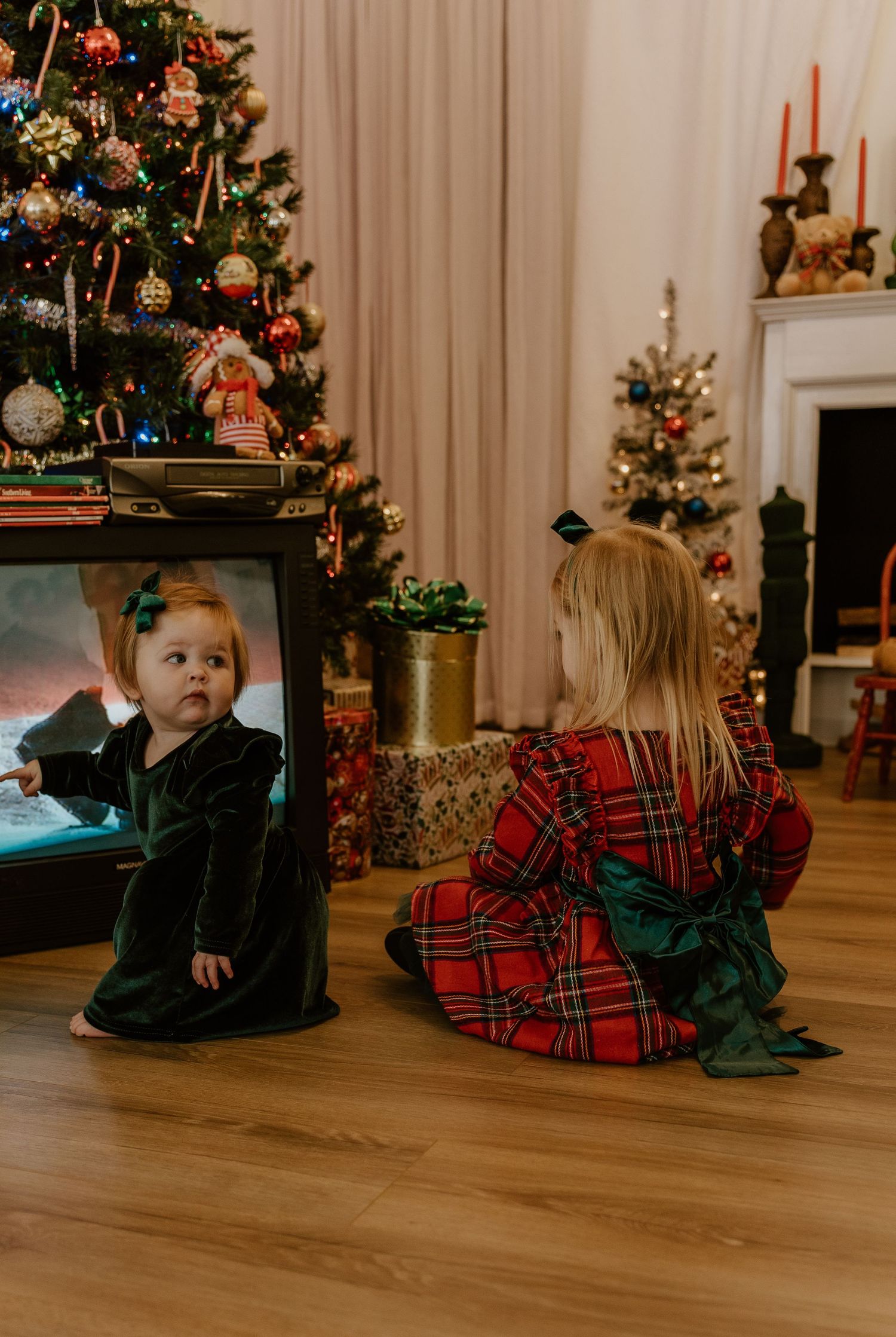 A series of holiday photos showing people sitting on a wooden floor in front of a decorated Christmas tree.