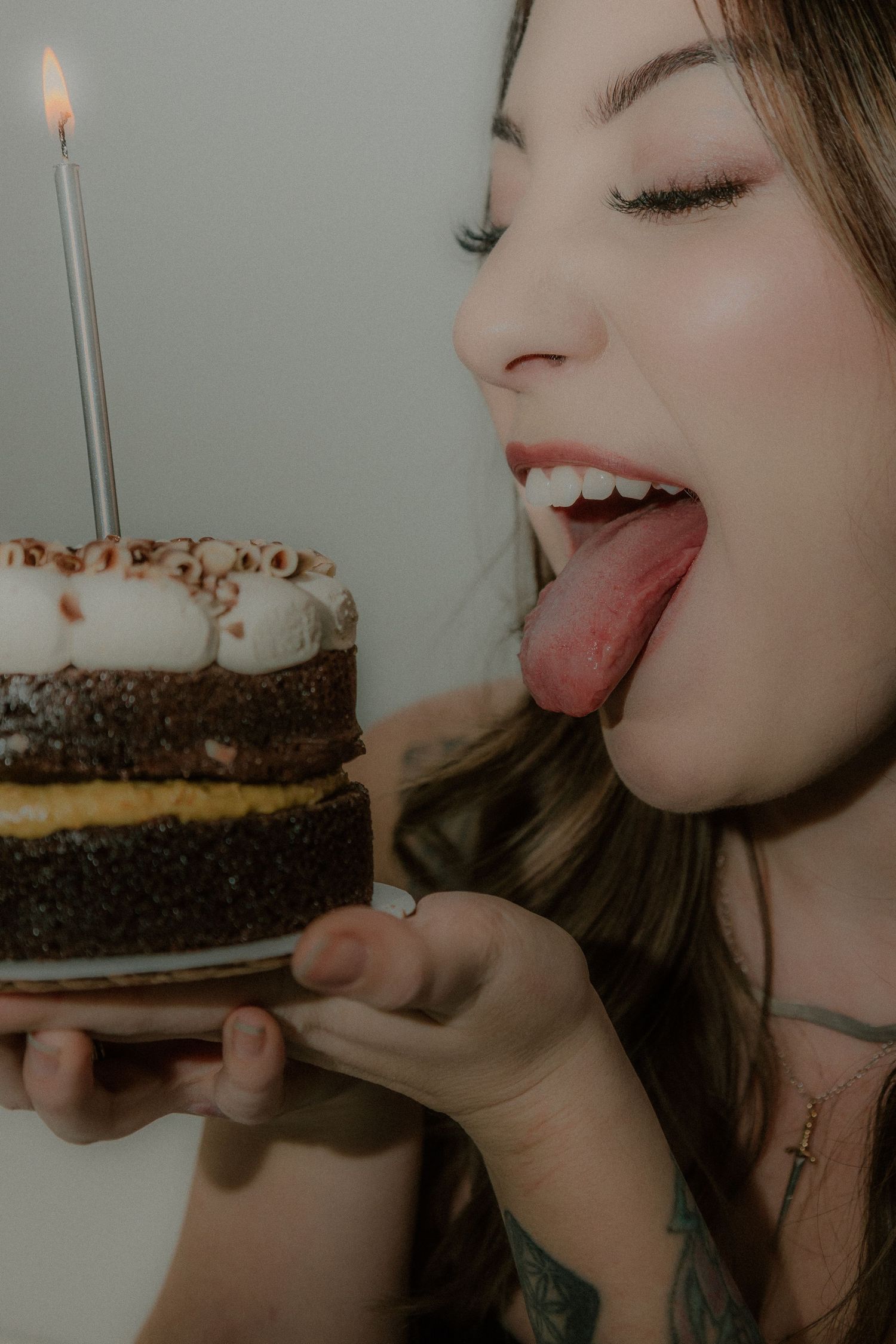 A series of photos showing someone playfully eating and enjoying a slice of chocolate birthday cake with a lit candle.